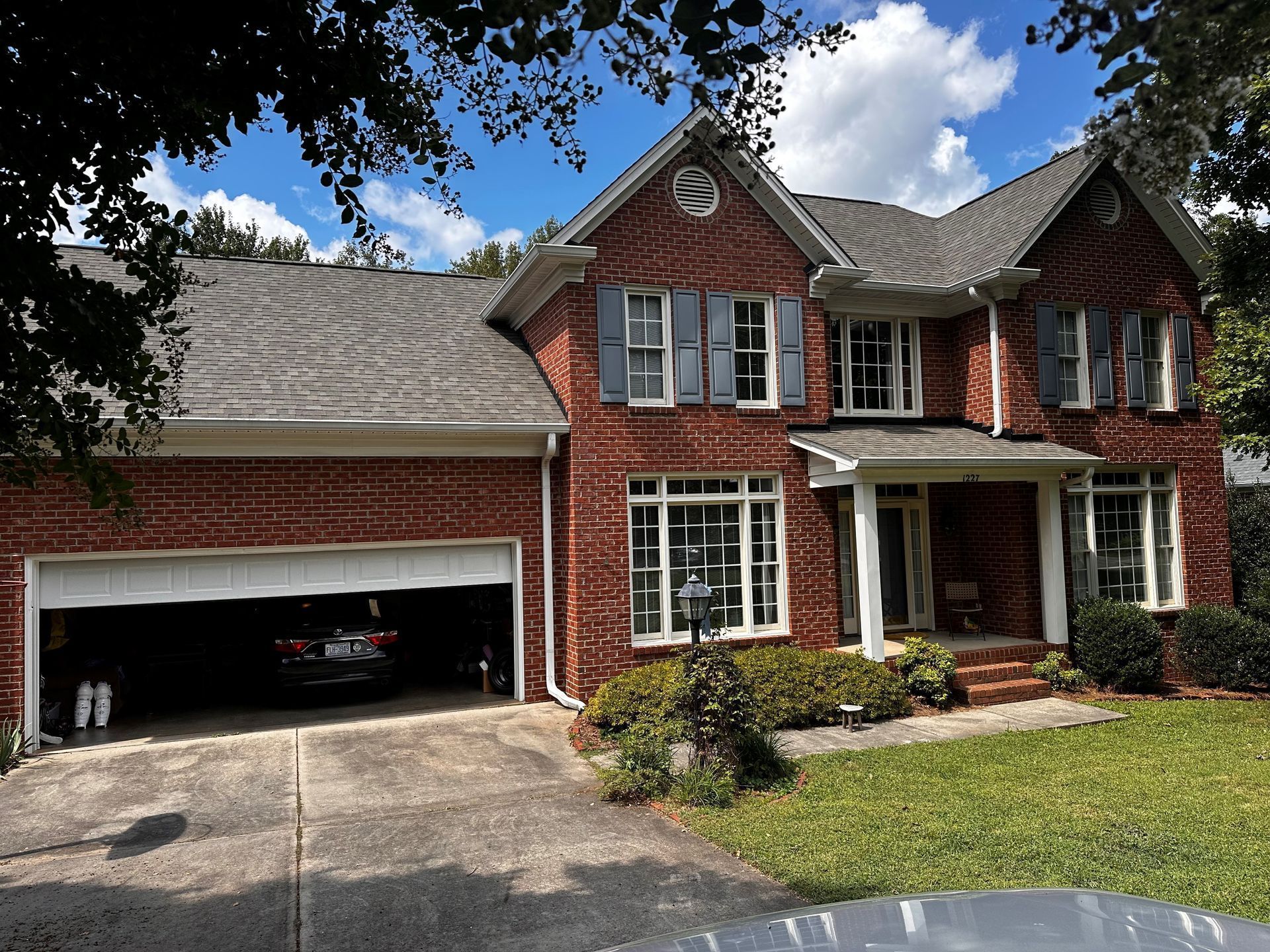 A large brick house with a car parked in the garage.