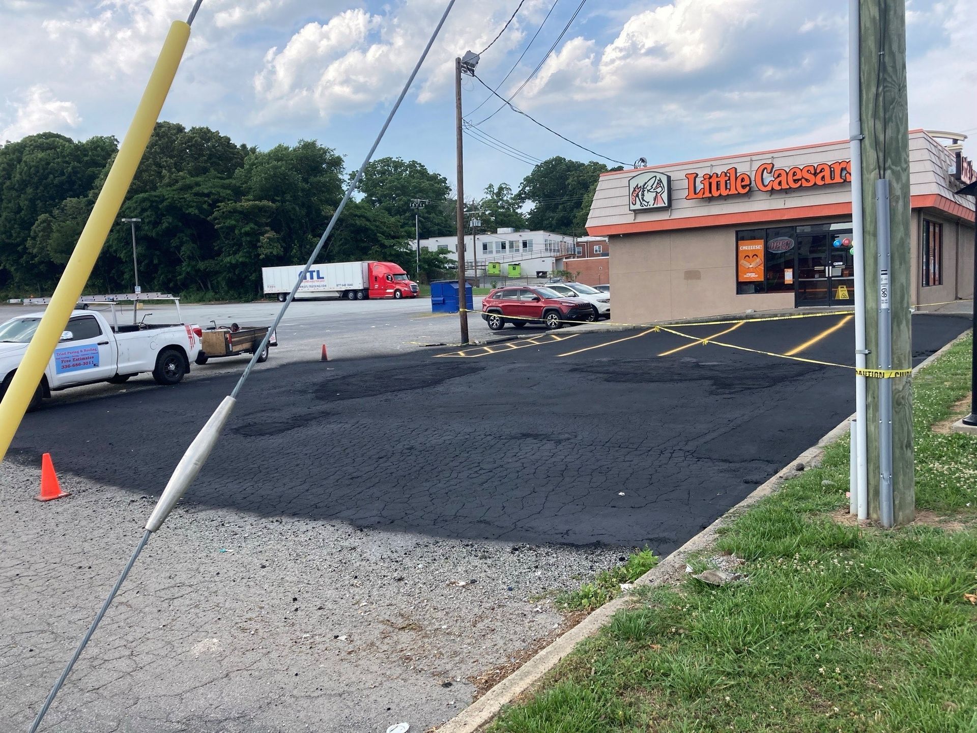 A white truck is parked in front of a little caesars restaurant