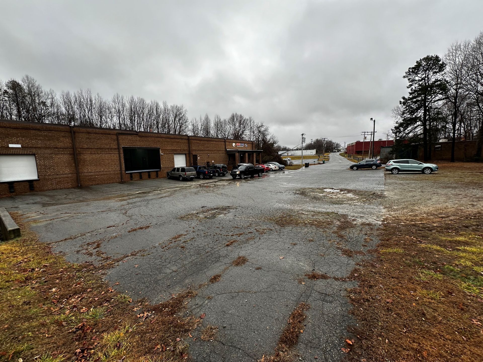 A parking lot with cars parked in front of a brick building on a cloudy day.