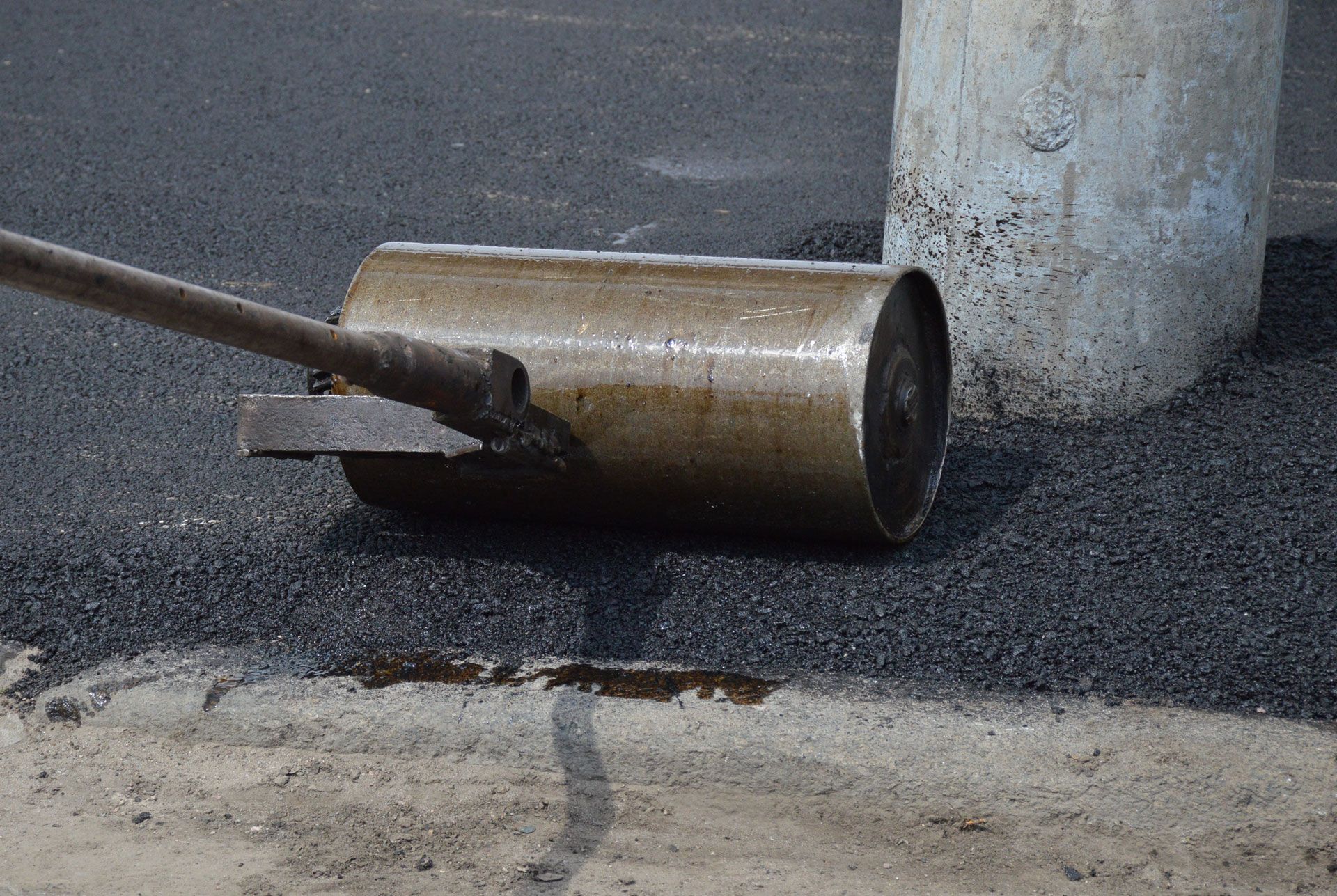 A roller is laying on the ground next to a pole.