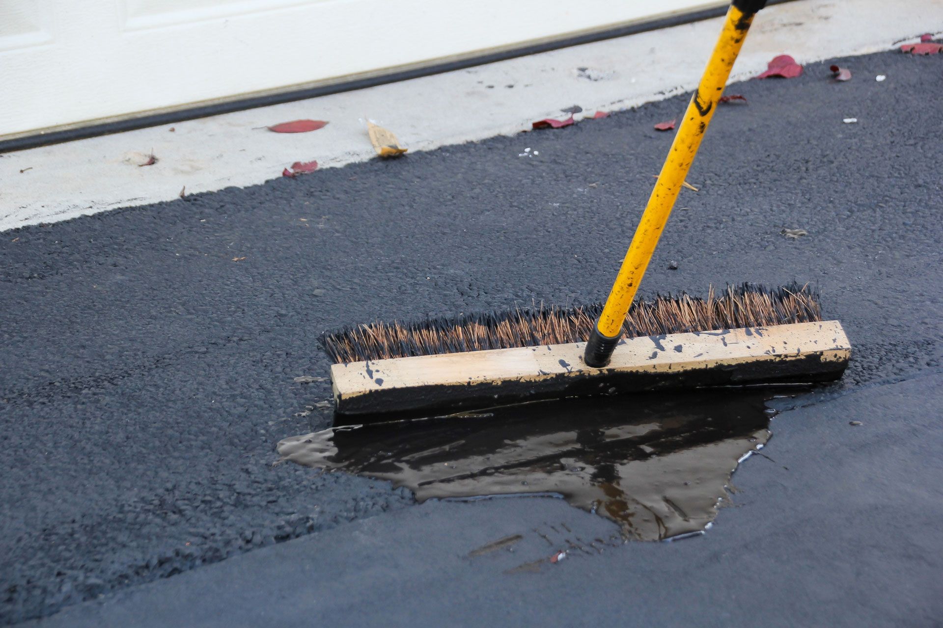 A broom is being used to clean a puddle of water on the ground