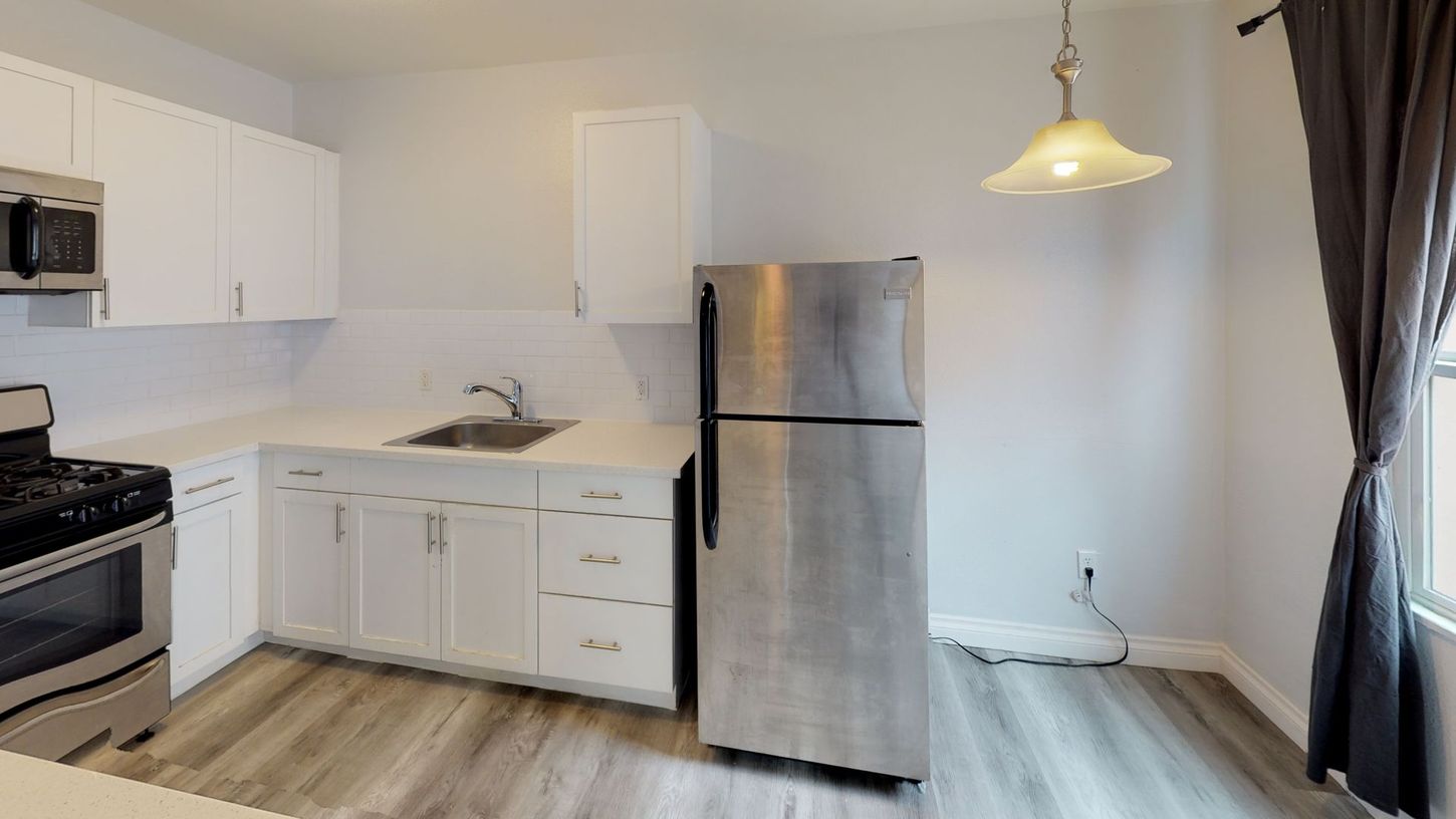 Kitchen with white cabinets, stainless steel appliances, and a light fixture hanging above.