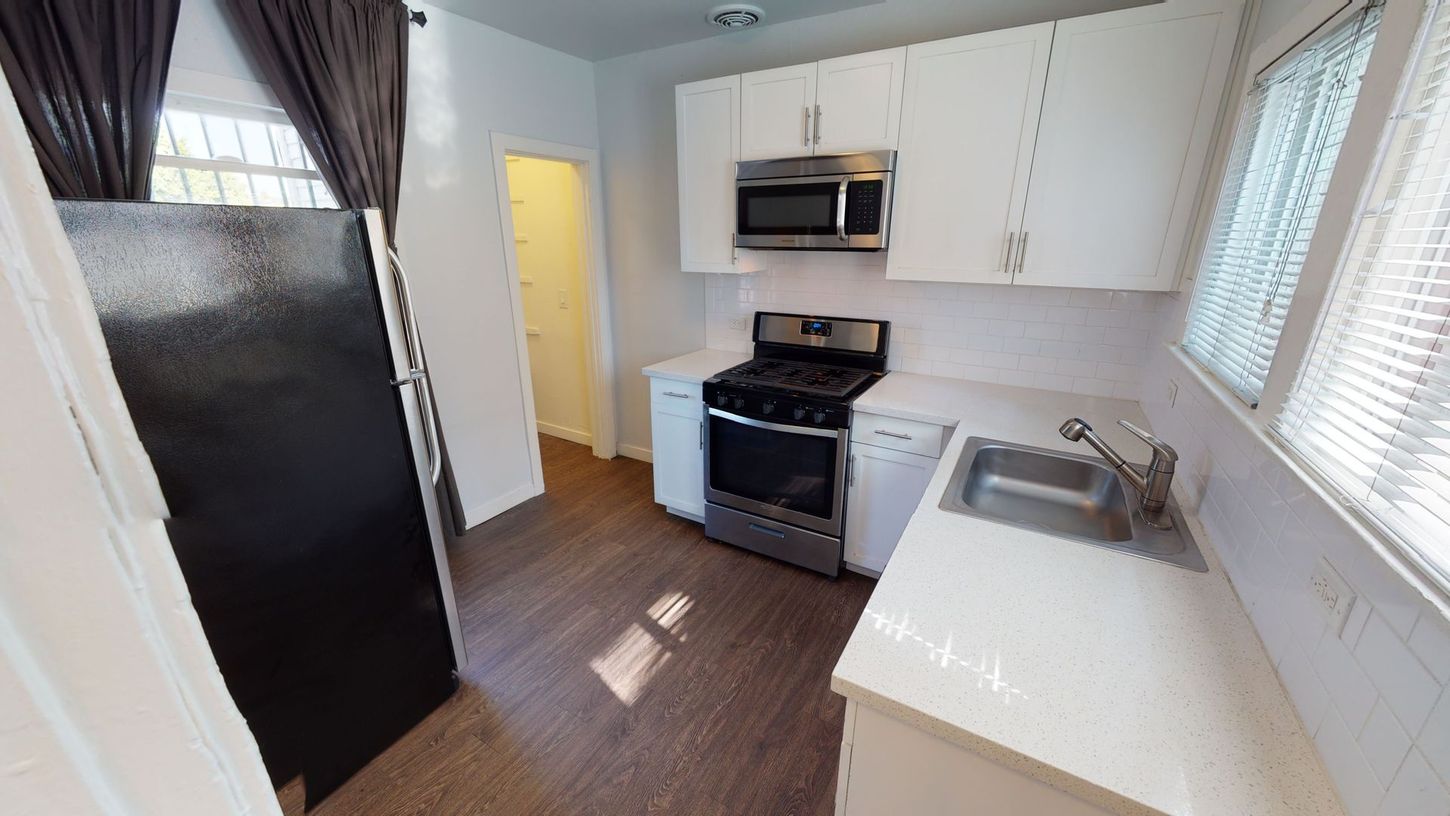 Kitchen with white cabinets, stainless steel appliances, and dark flooring.