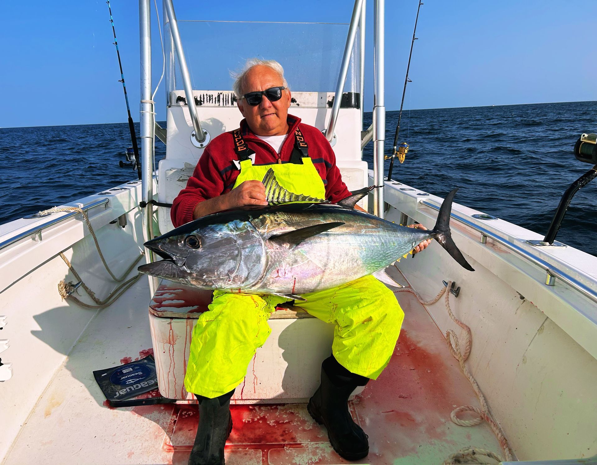A man is sitting on a boat holding a large fish