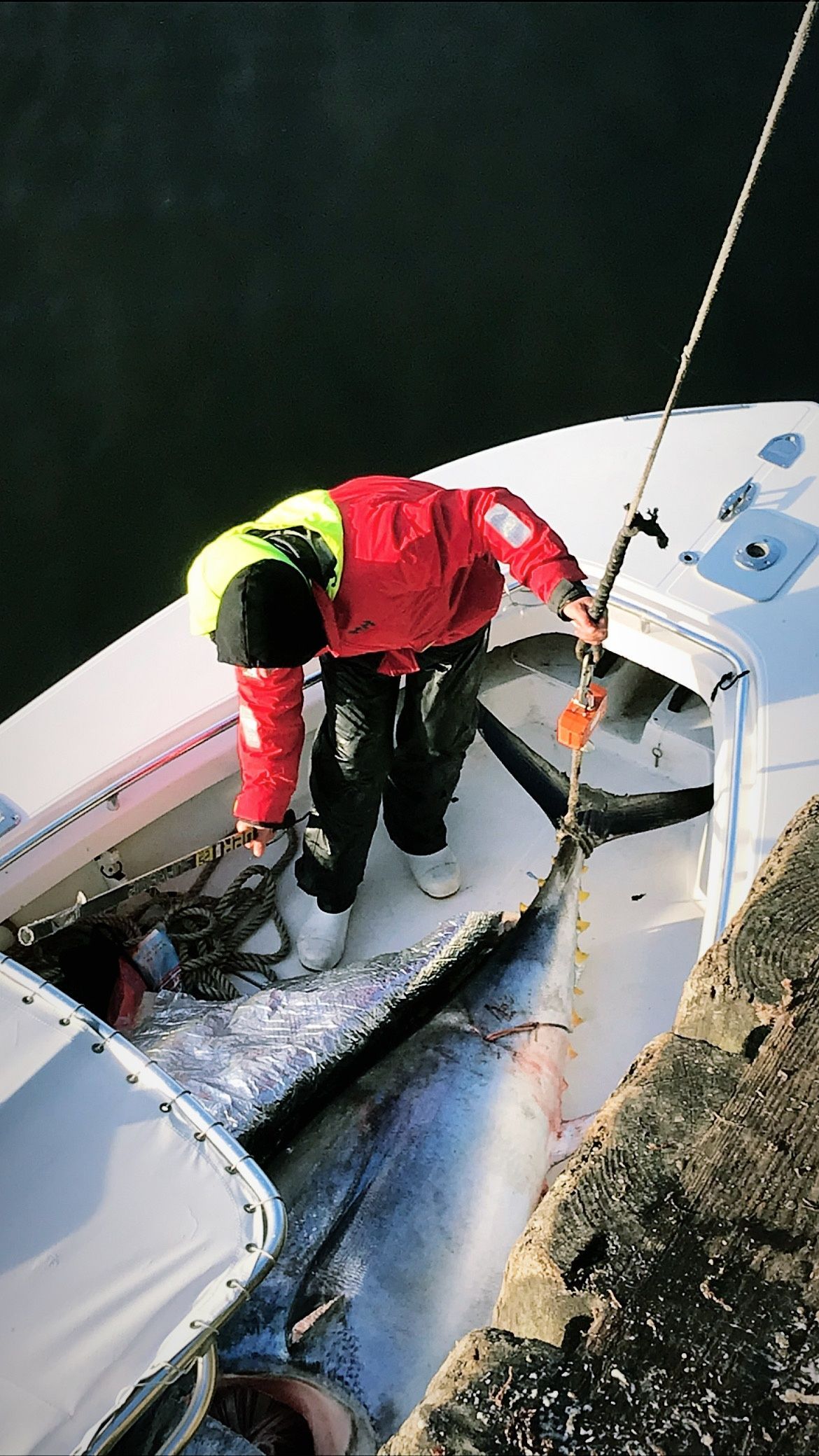 A man in a red jacket is fishing on a boat