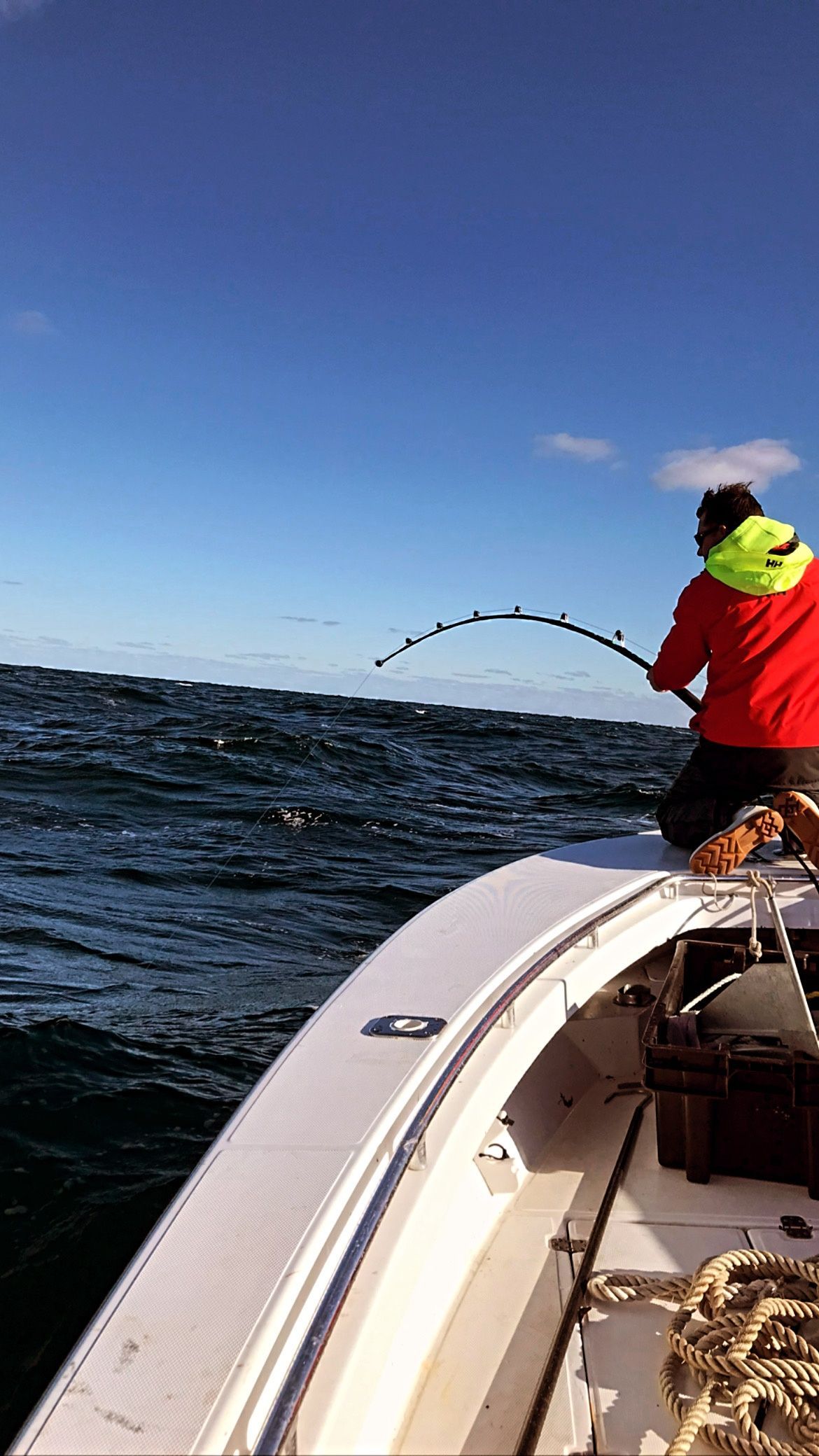 A man is fishing on a boat in the ocean