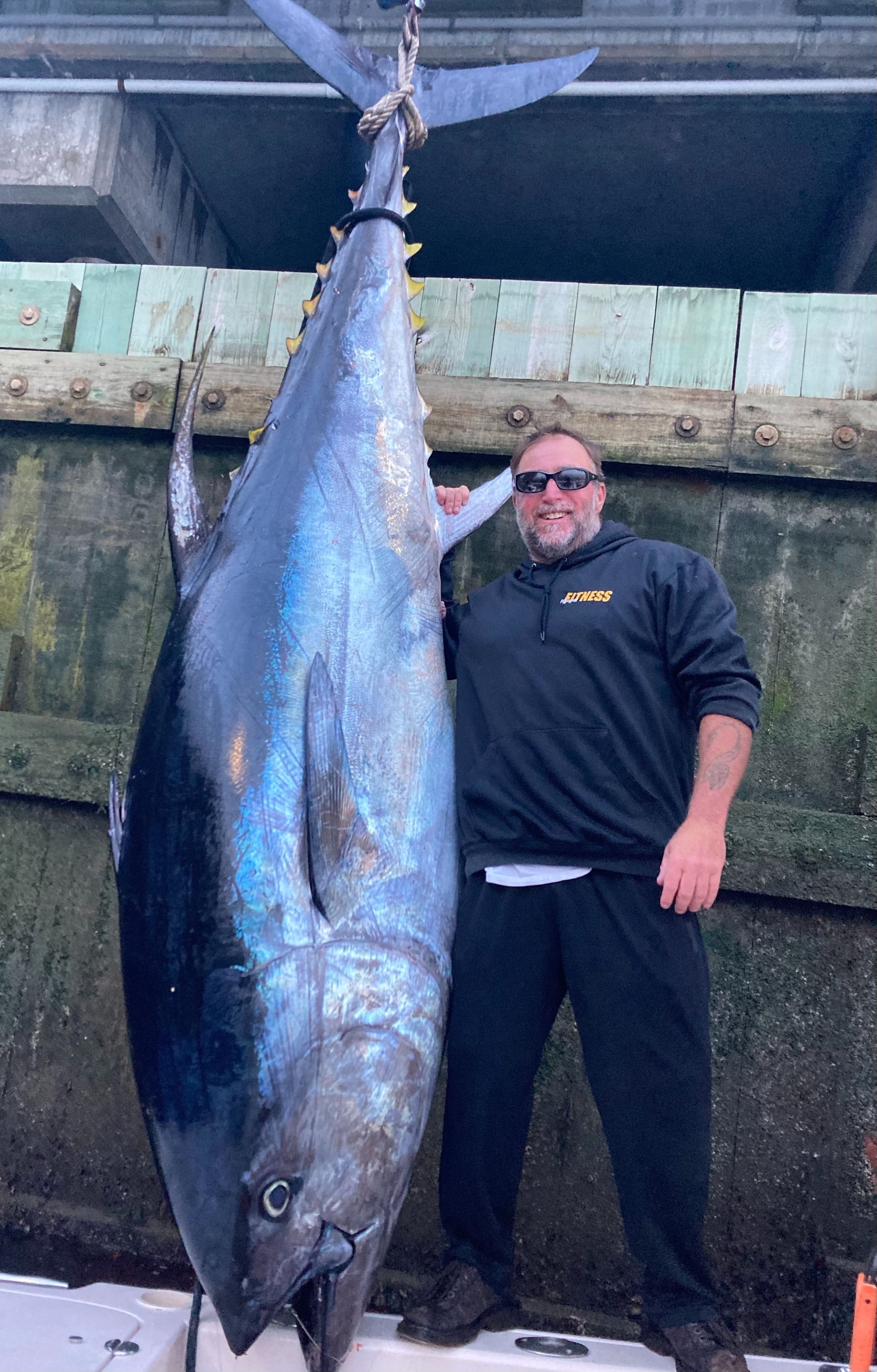A man is standing next to a large fish on a boat.