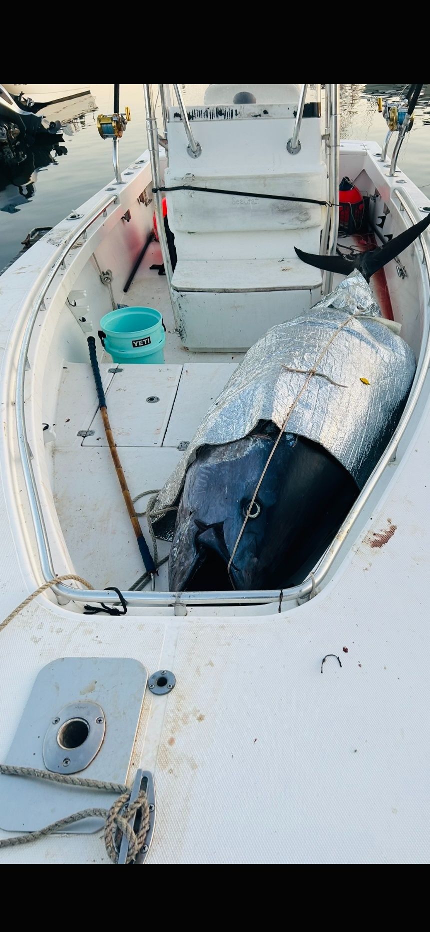 A boat with a large object in the back of it is sitting in the water.