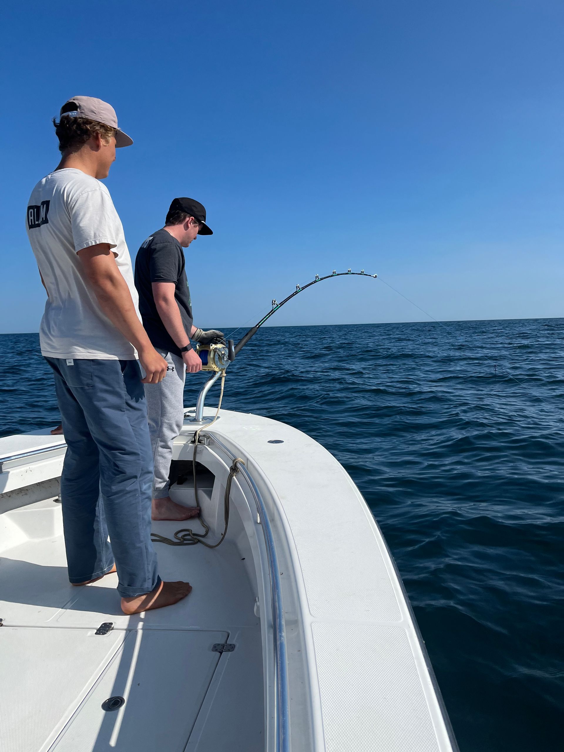 Two men are fishing on a boat in the ocean.