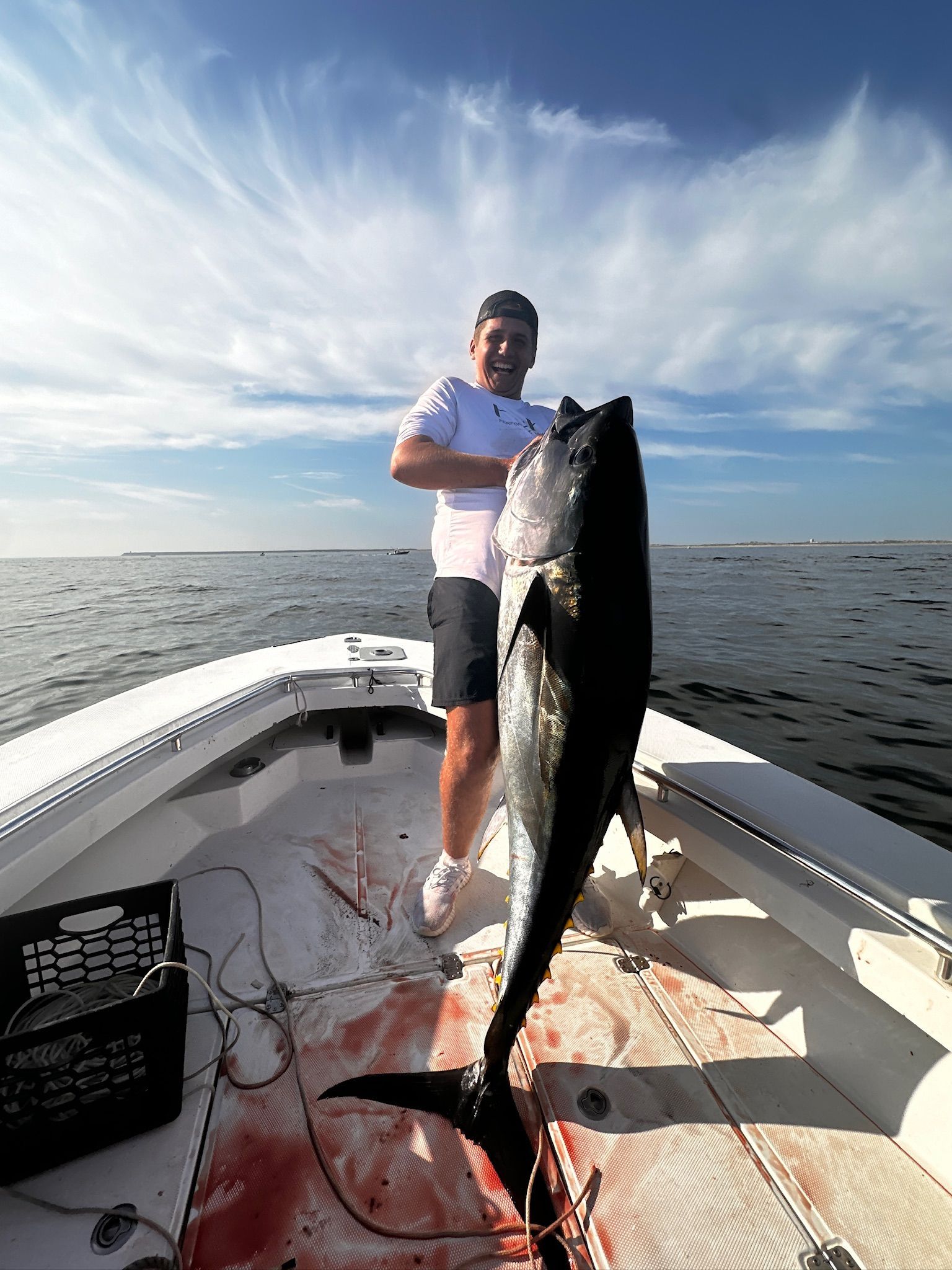 A man is standing on a boat holding a large fish.