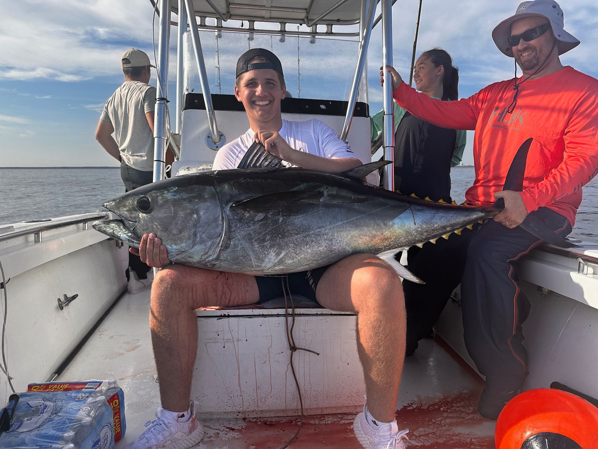 A man is sitting on a boat holding a large fish.