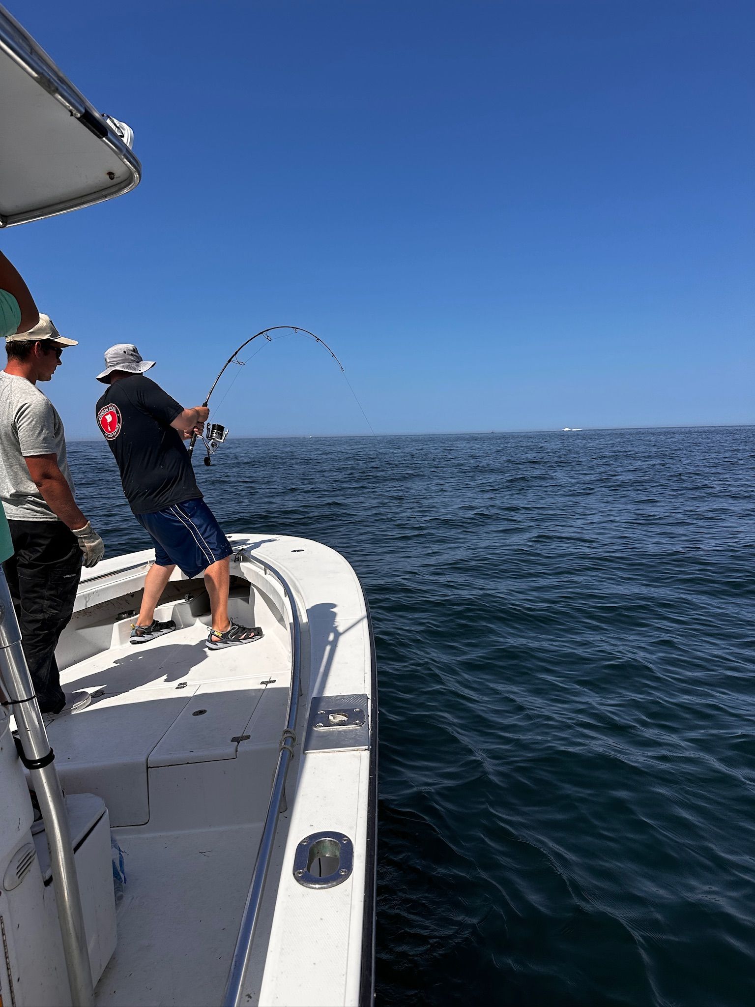 A man is fishing on a boat in the ocean.