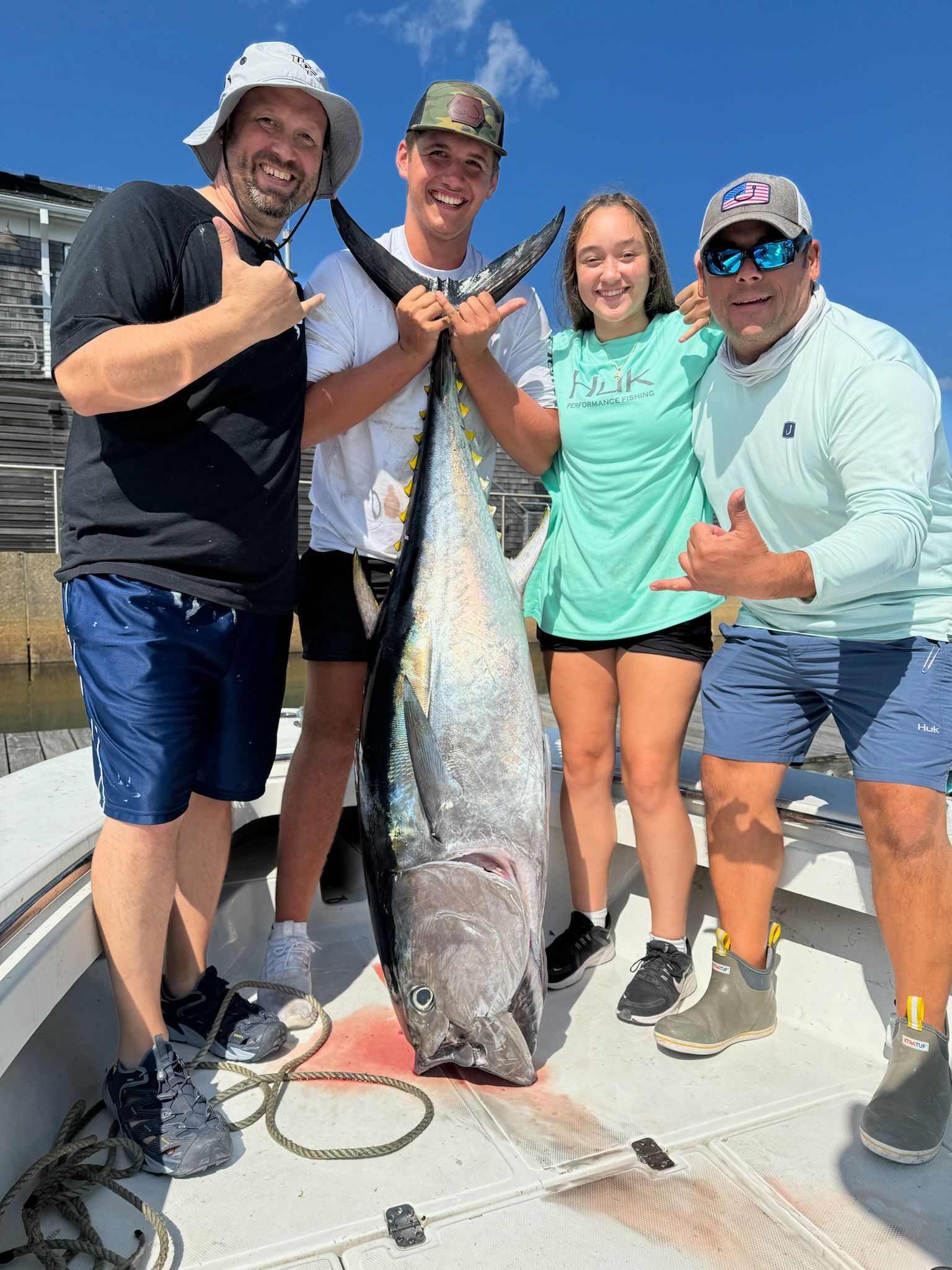 A group of people are standing on a boat holding a large fish.