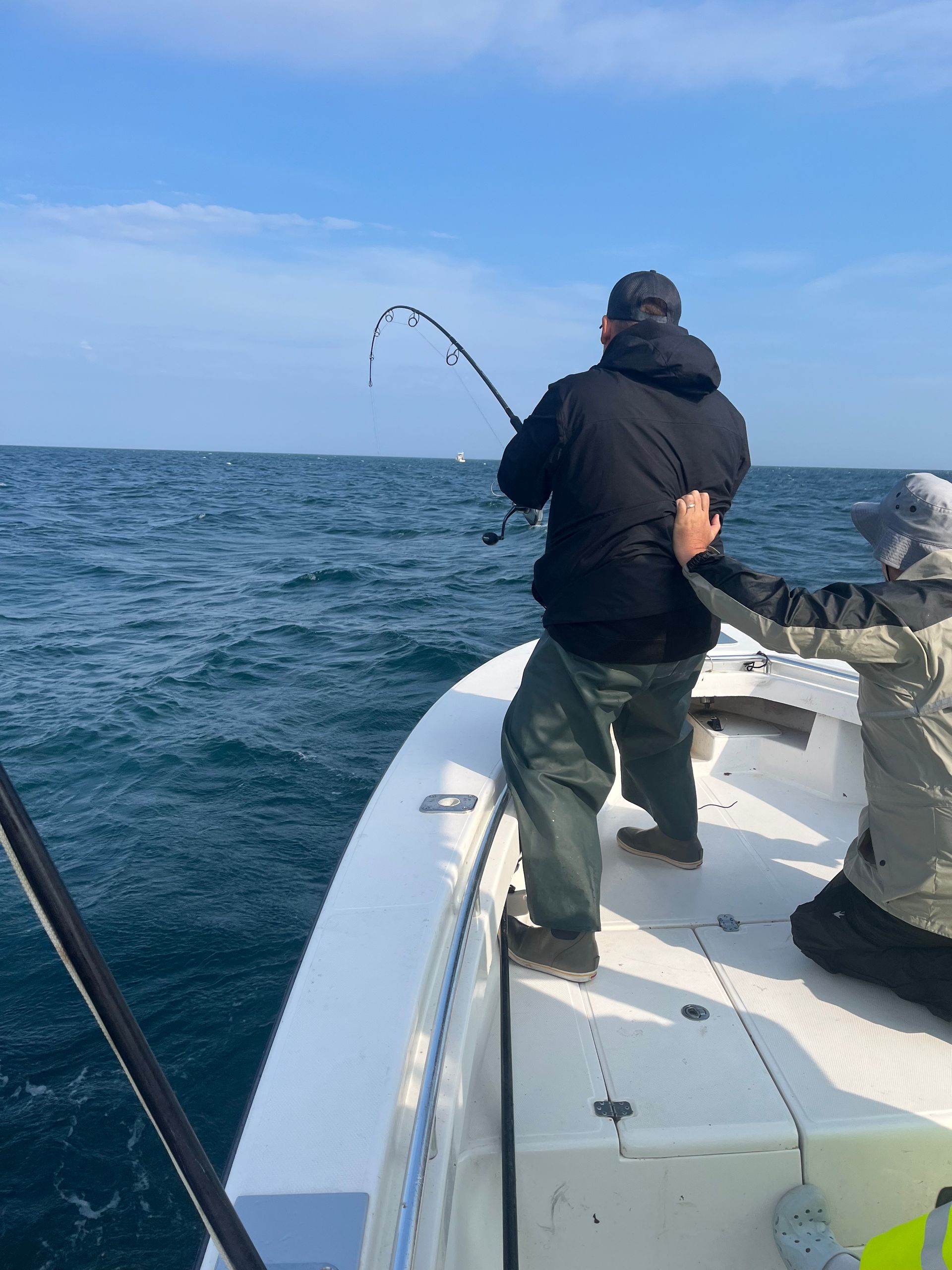 Two men are fishing on a boat in the ocean.