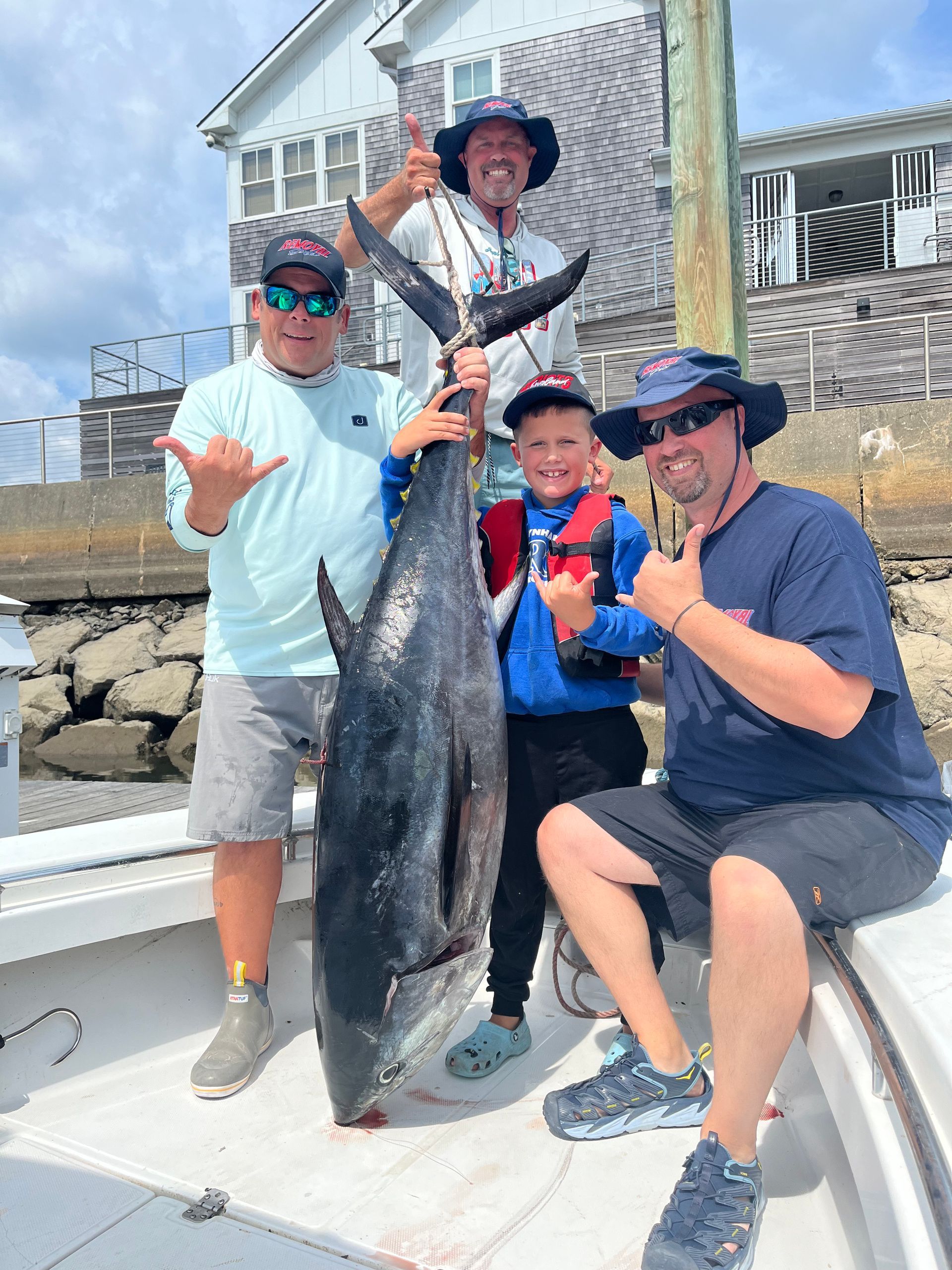 A group of men are standing on a boat holding a large fish.