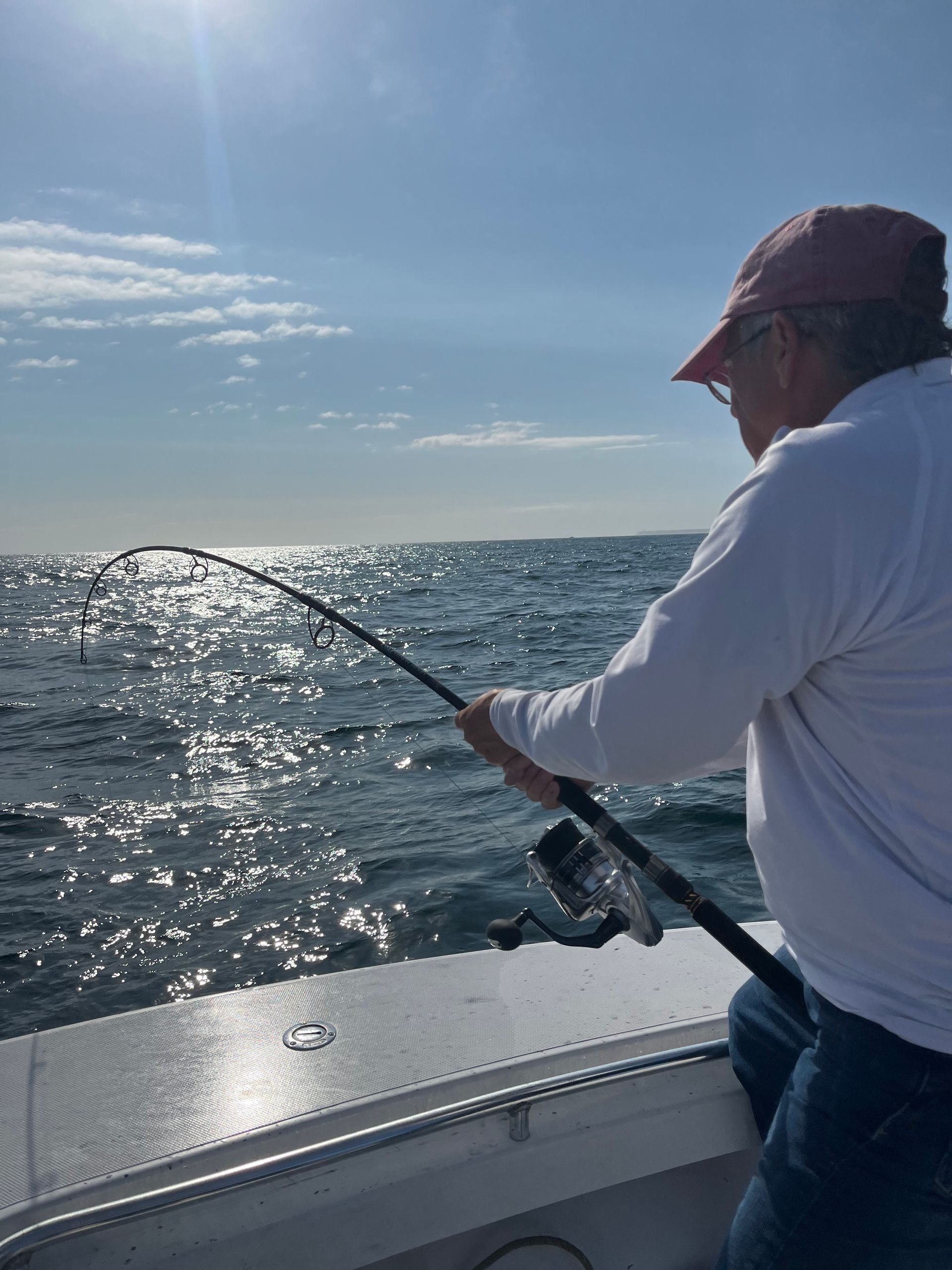 A man is fishing in the ocean on a boat.