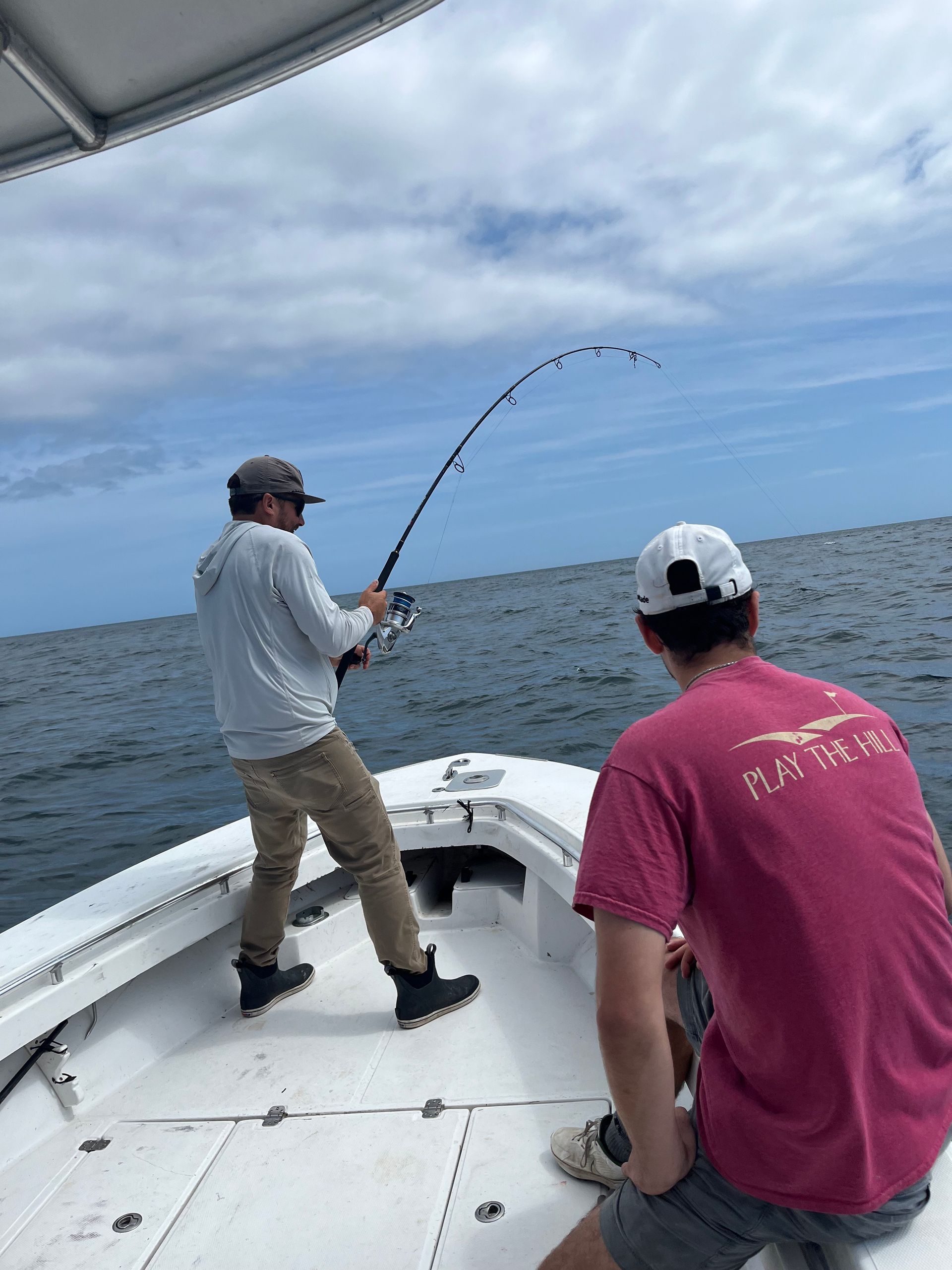 Two men are fishing on a boat in the ocean.