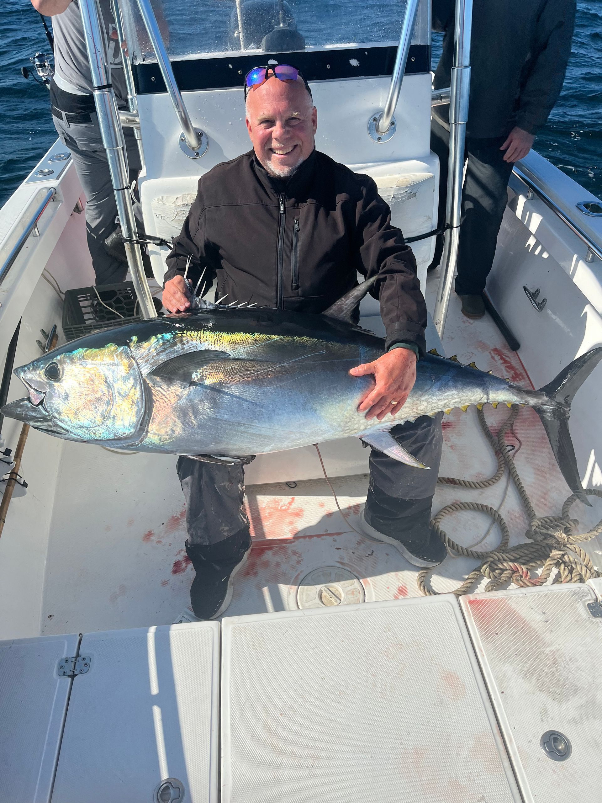 A man is holding a large fish on a boat.