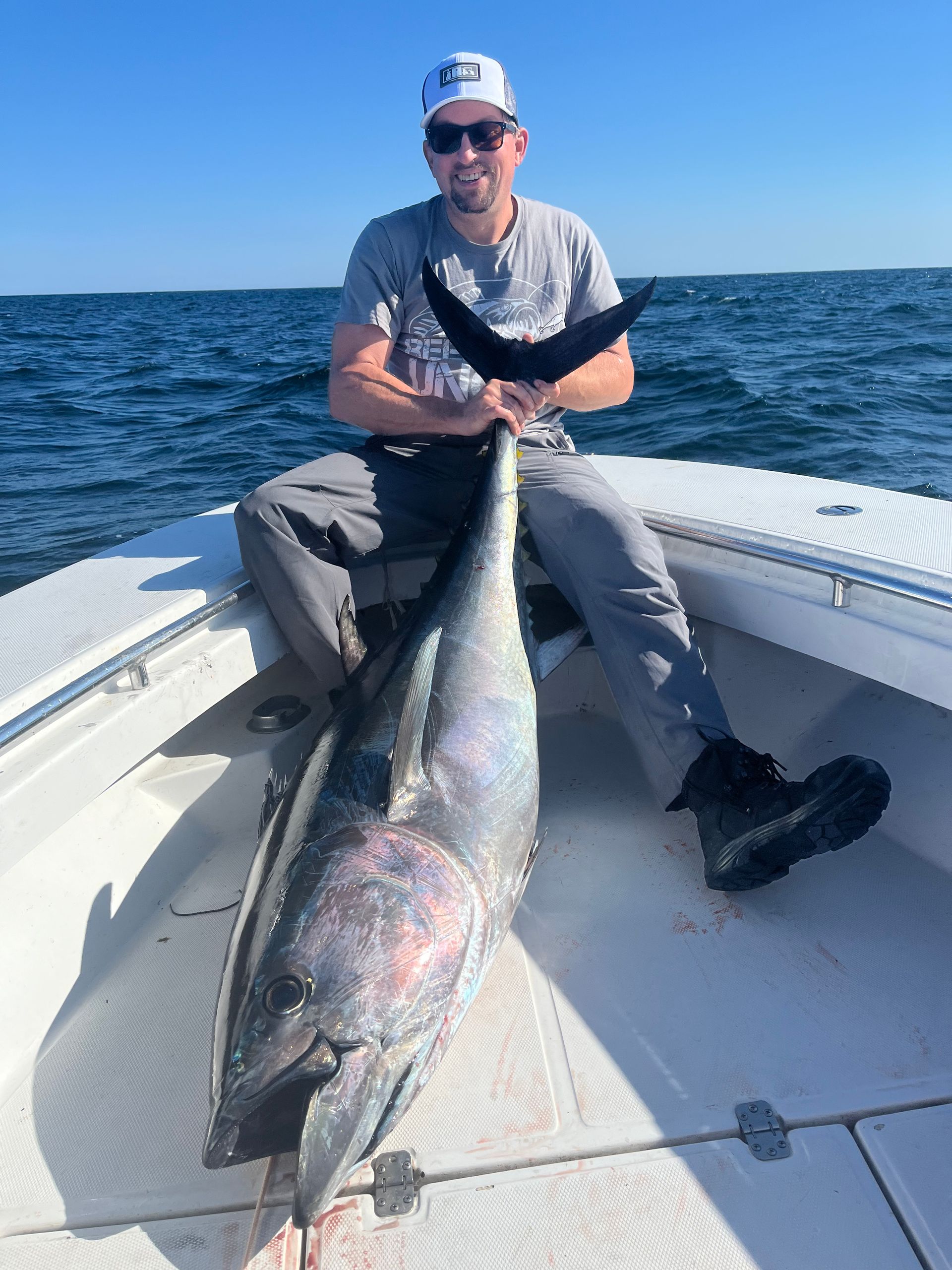 A man is sitting on a boat holding a large fish.