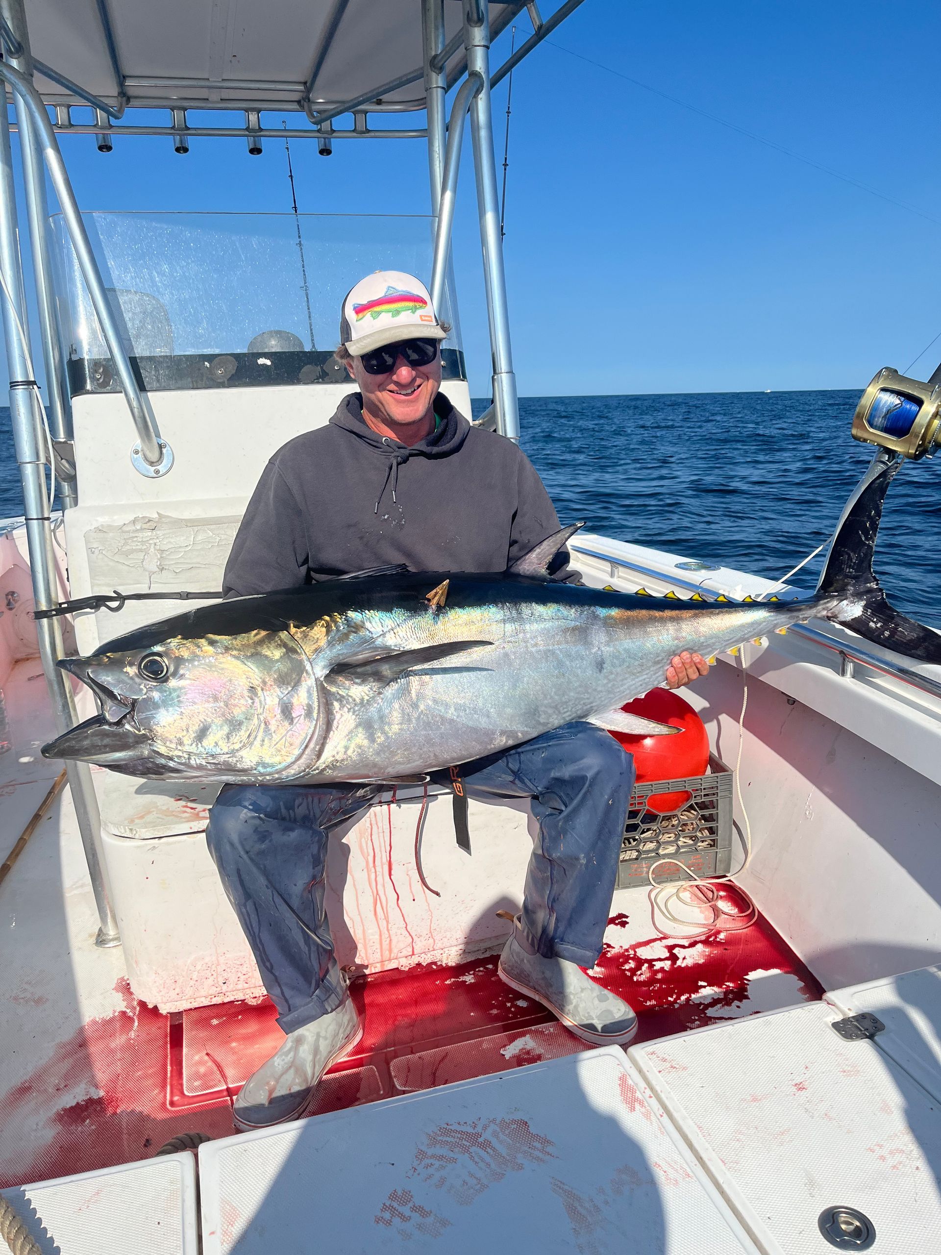 A man is sitting on a boat holding a large fish.