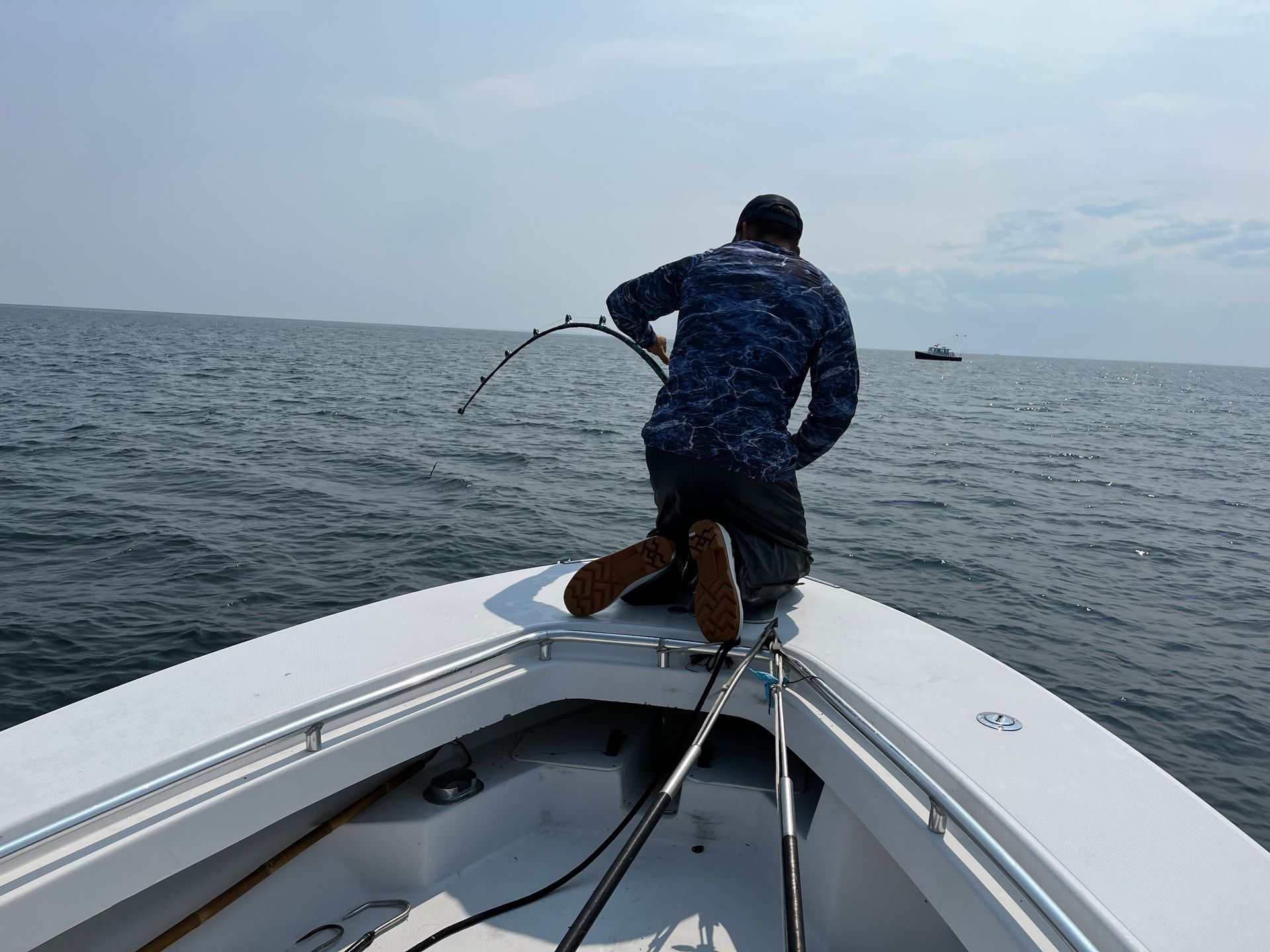 A man is fishing on a boat in the ocean