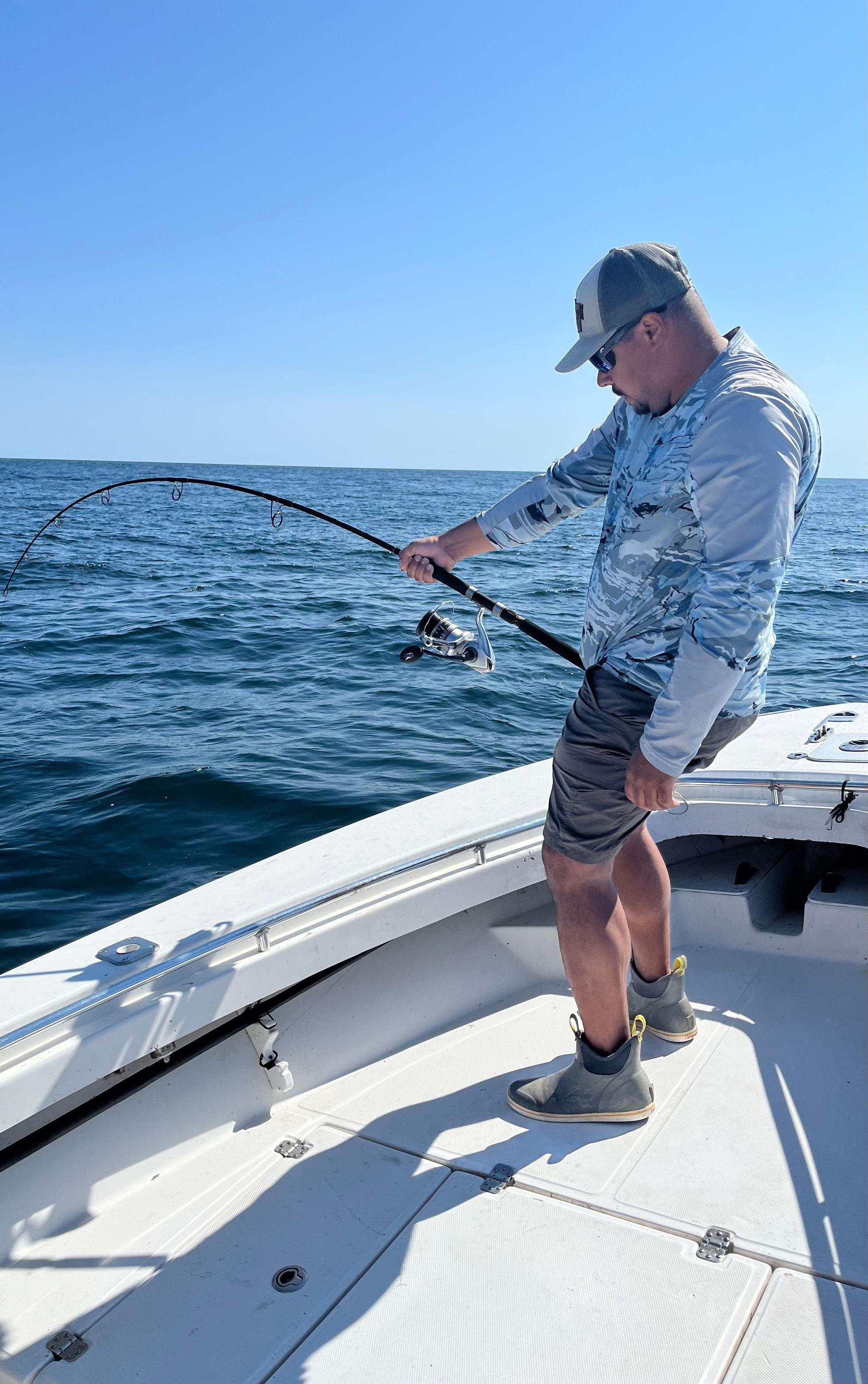 A man is fishing on a boat in the ocean.