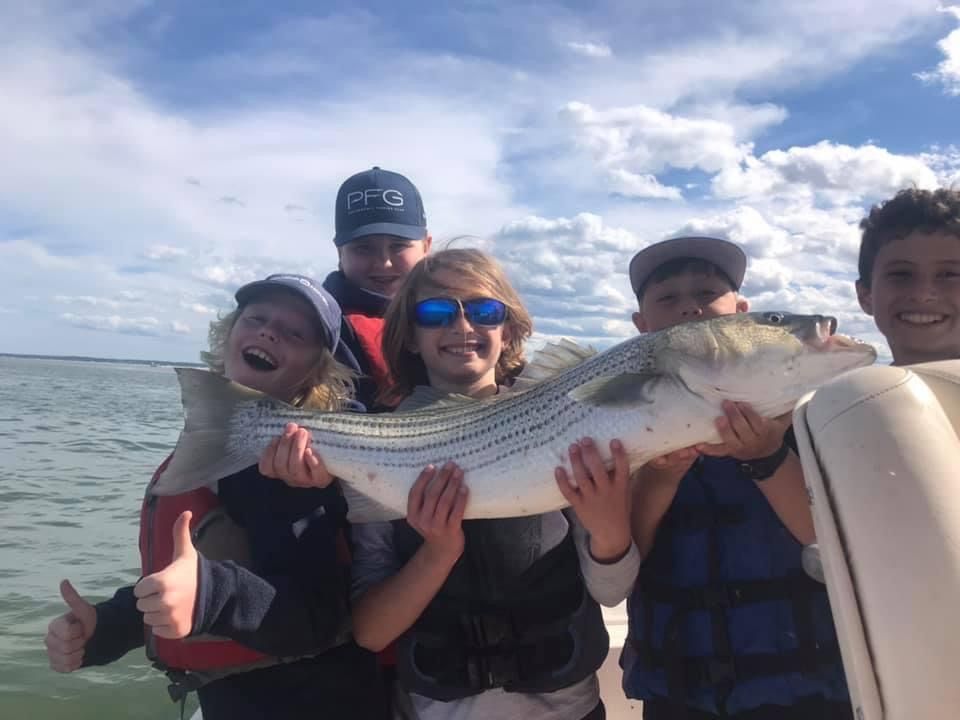 A group of people on a boat holding a large fish