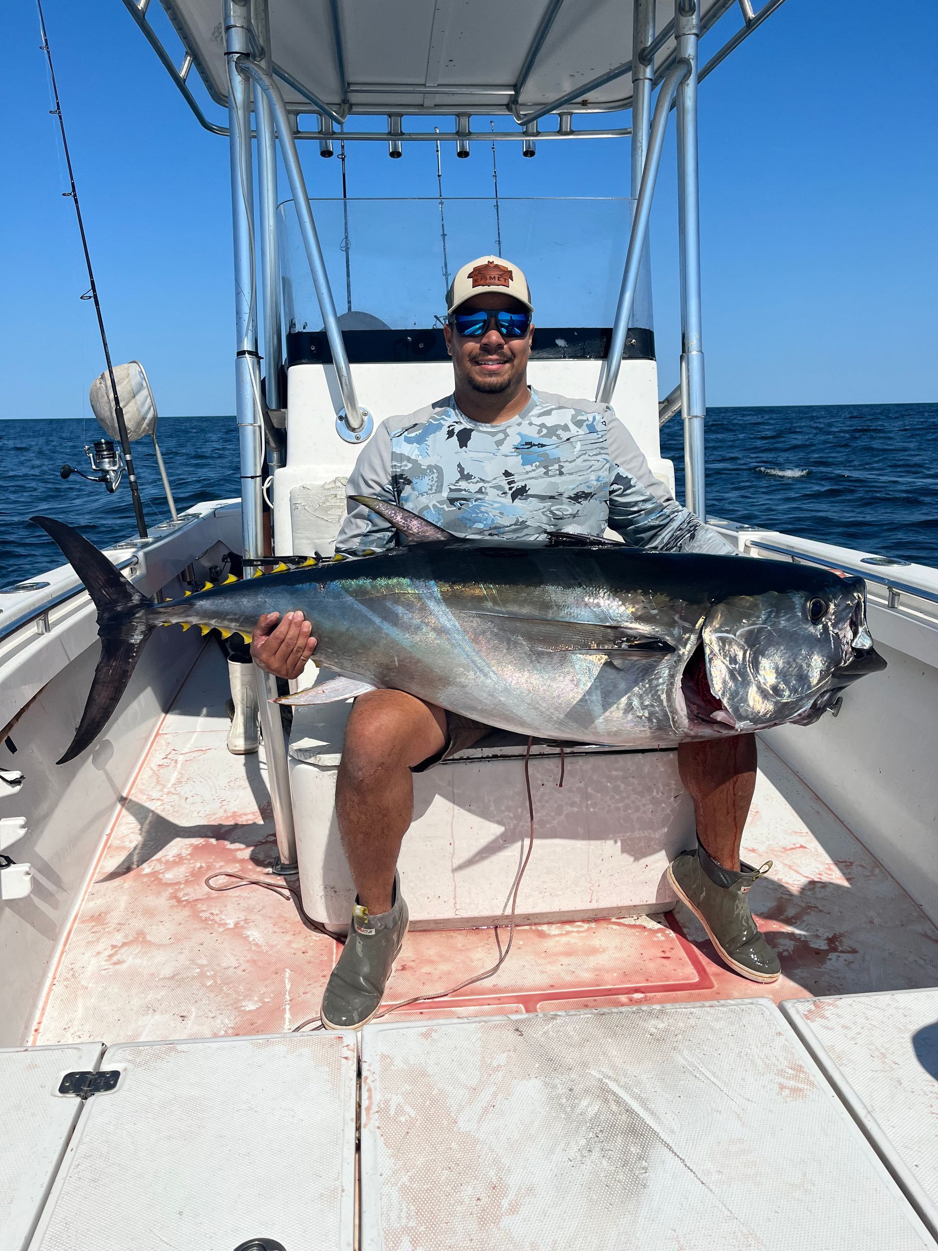 A man is sitting on a boat holding a large fish.