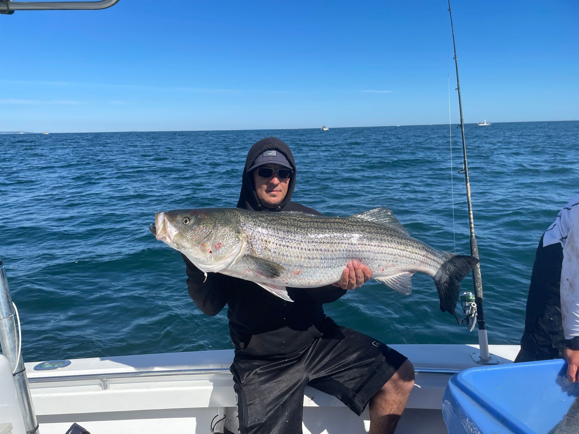 A man is sitting on a boat holding a large fish.