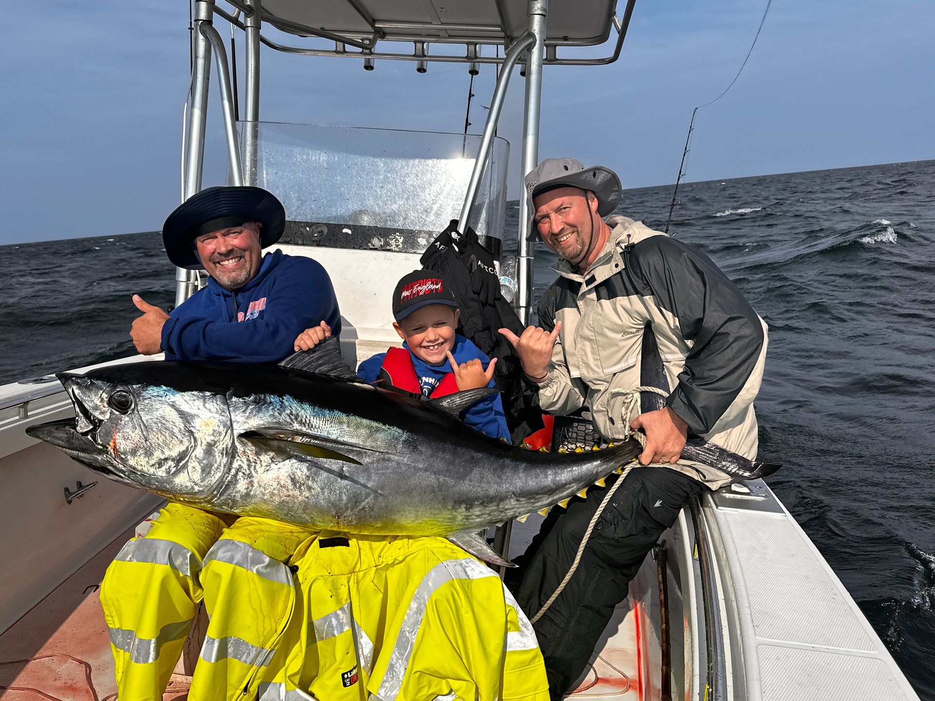 Two men and a boy are sitting on a boat holding a large fish.