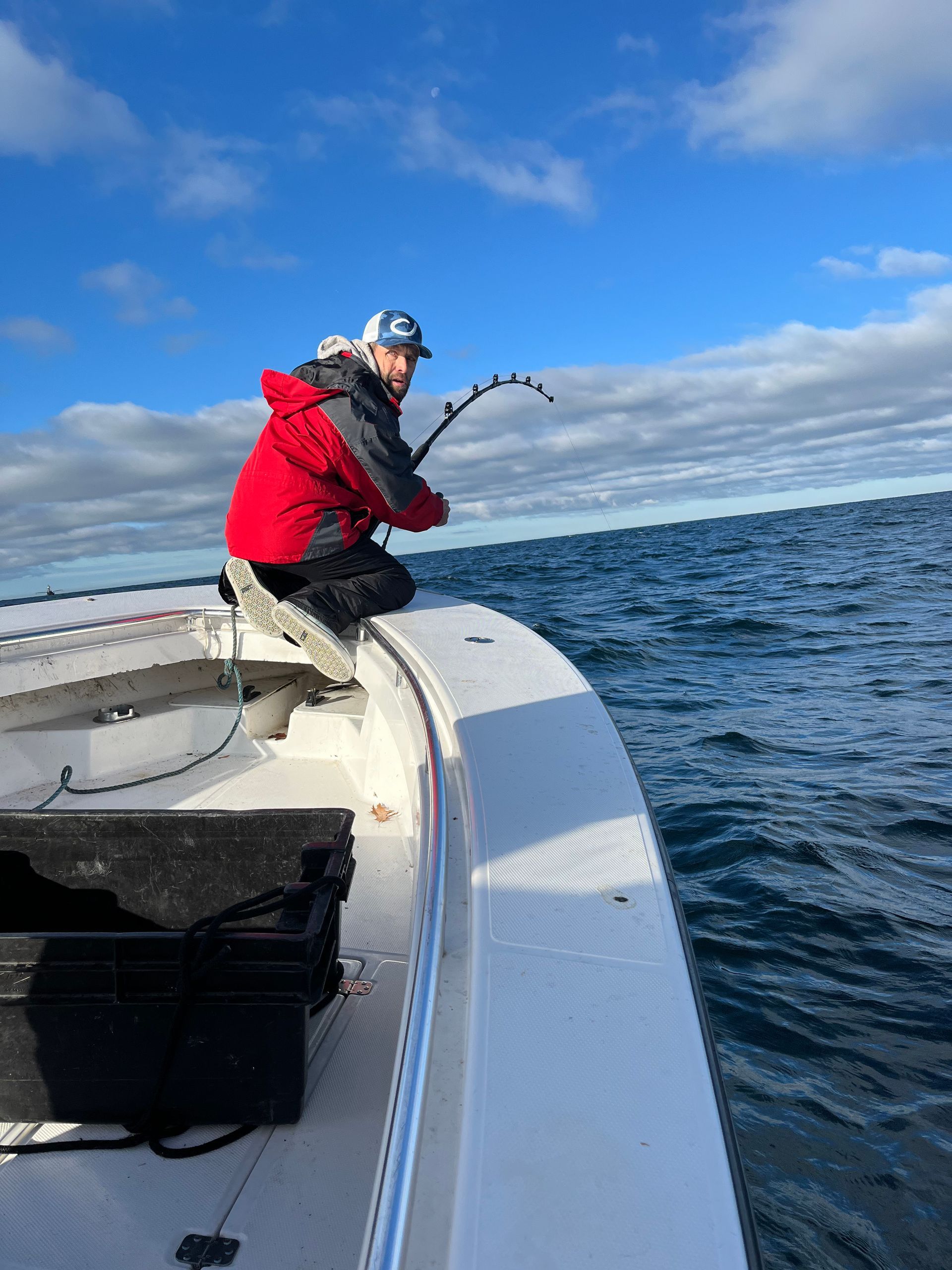 A man is fishing on a boat in the ocean.