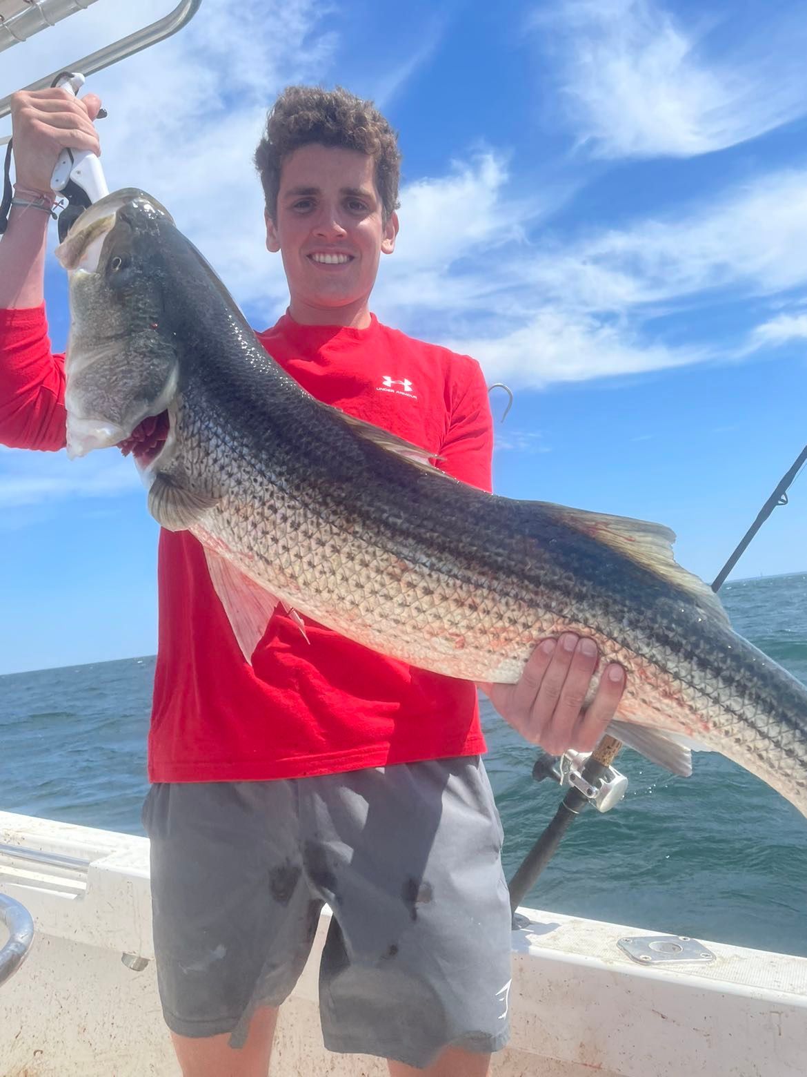 A young man is holding a large fish on a boat.