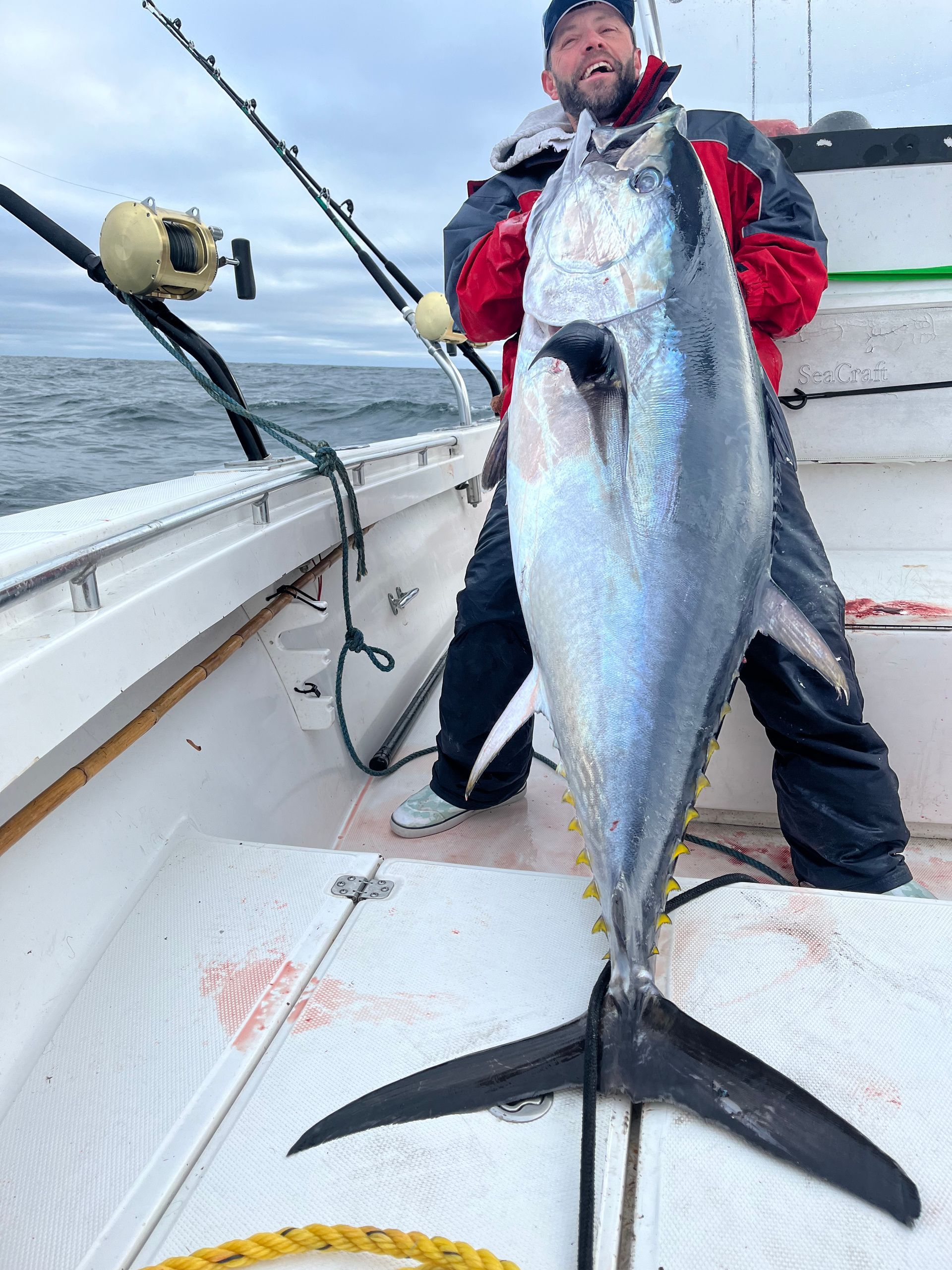A man is standing on a boat holding a large fish.