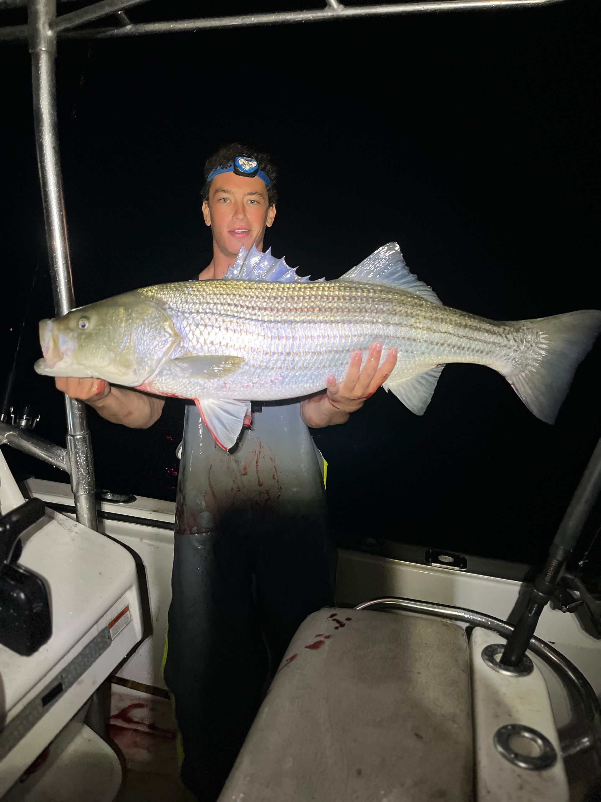 A man is holding a large fish in his hands on a boat.