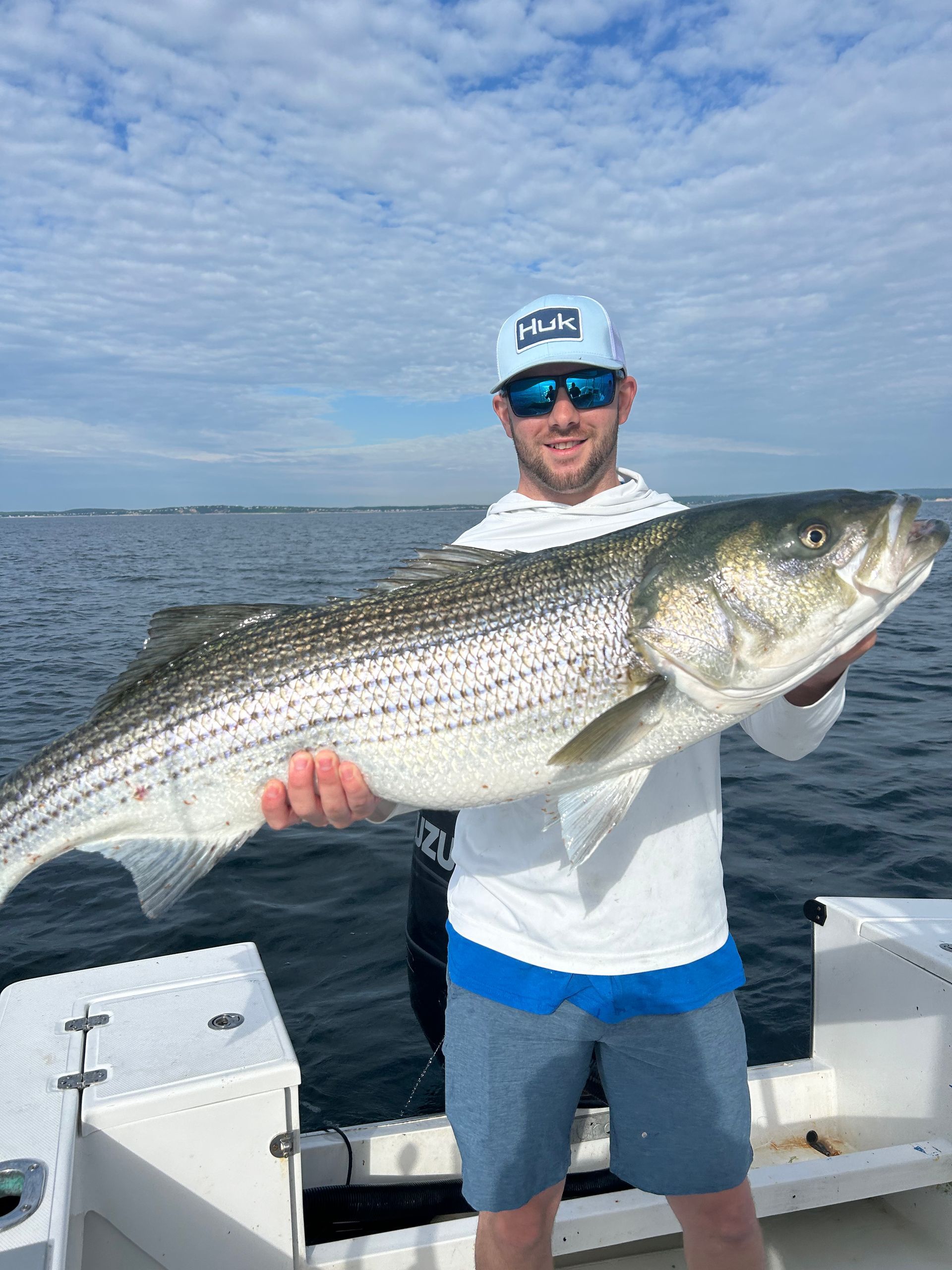 A man is holding a large fish on a boat.