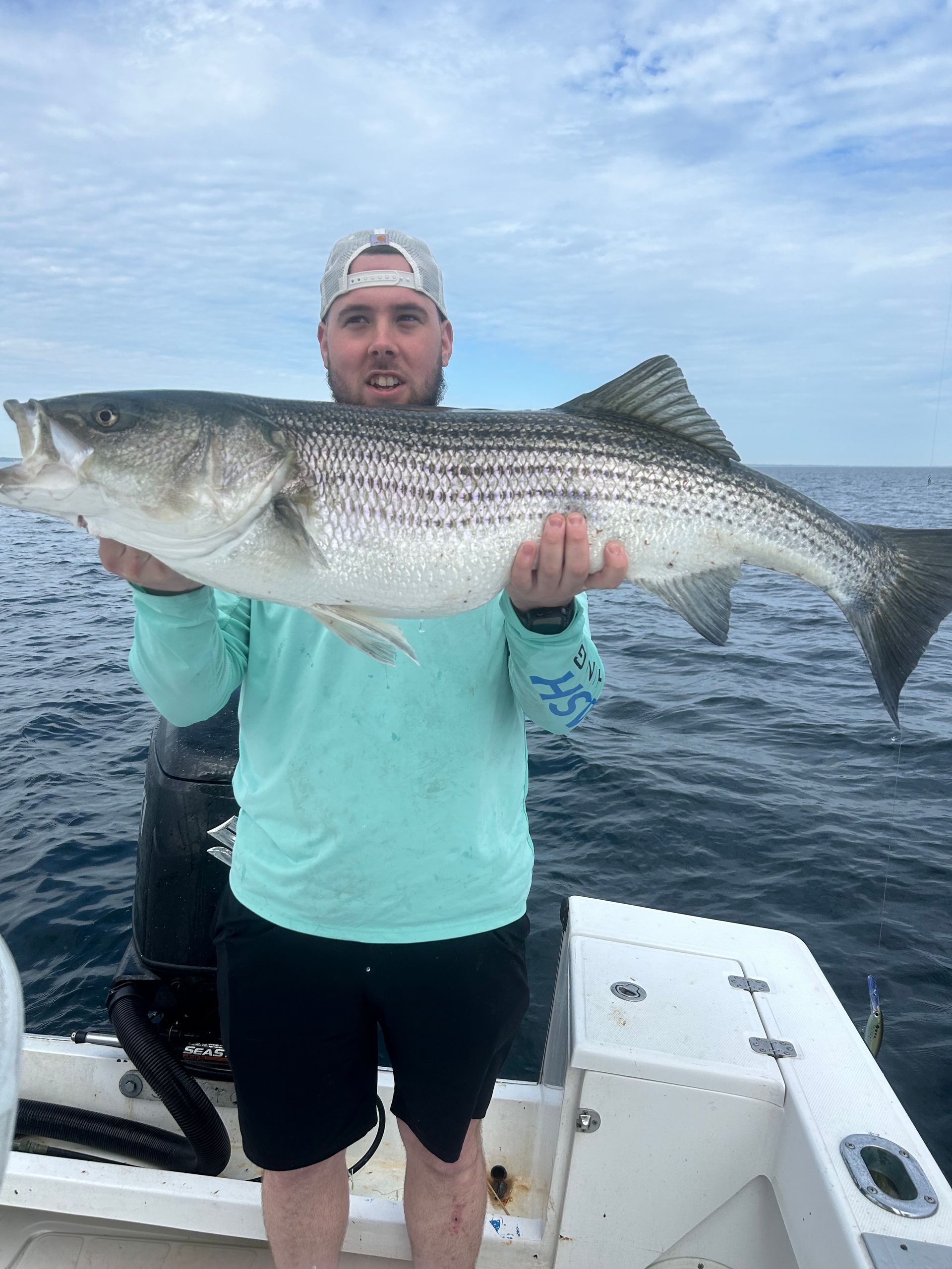 A man is holding a large fish on a boat in the ocean.