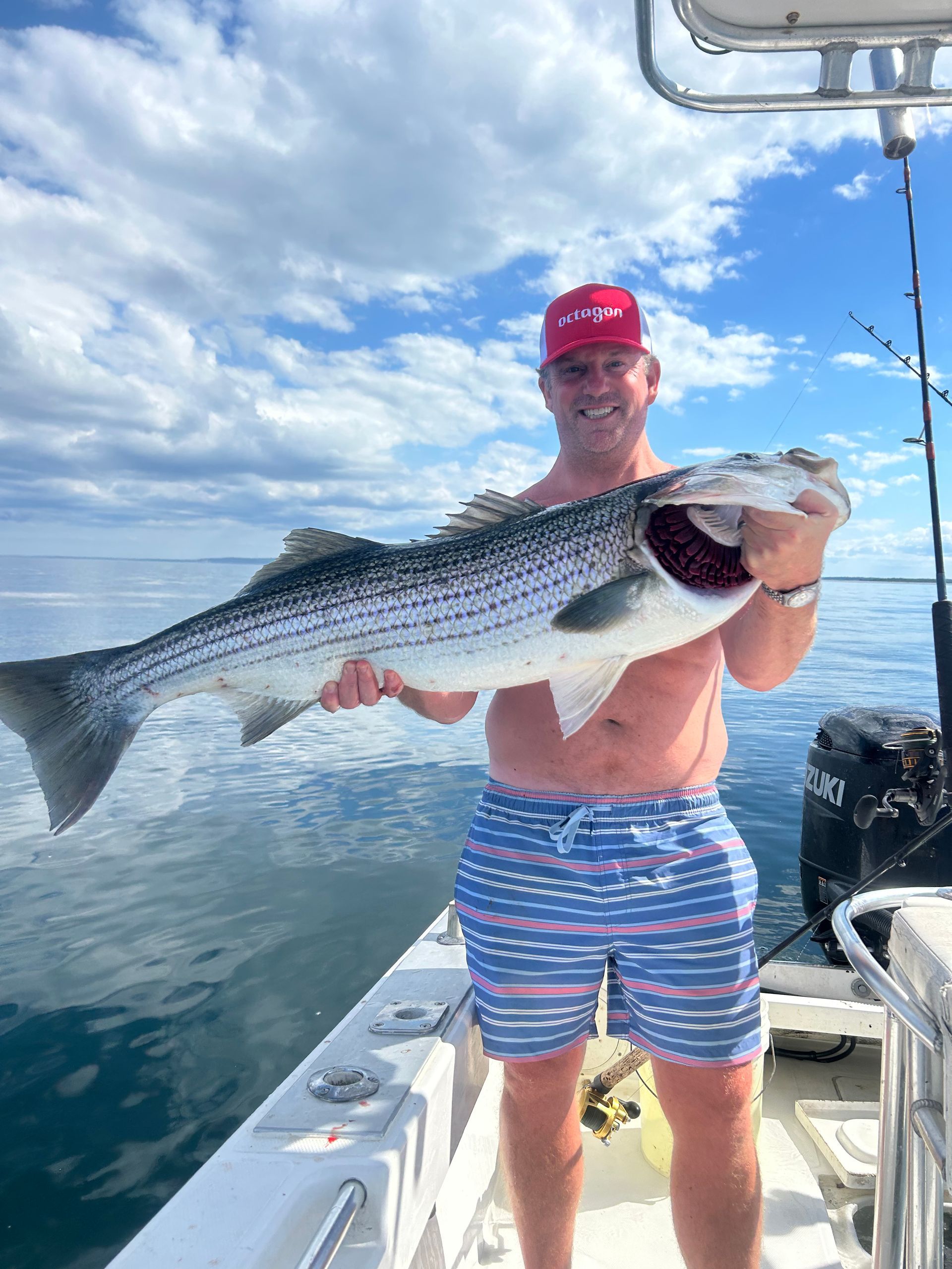 A man is holding a large fish on a boat.