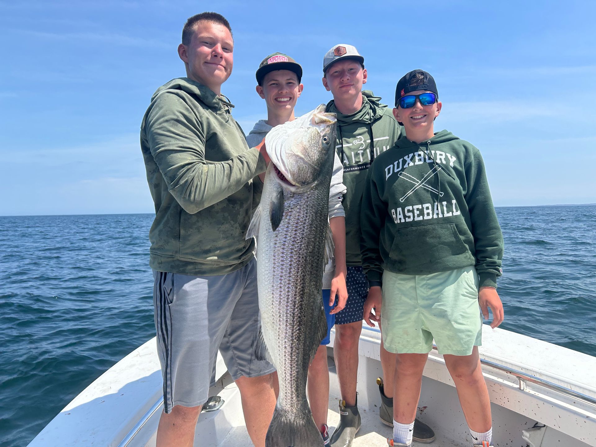 A group of men are standing on a boat holding a large fish.