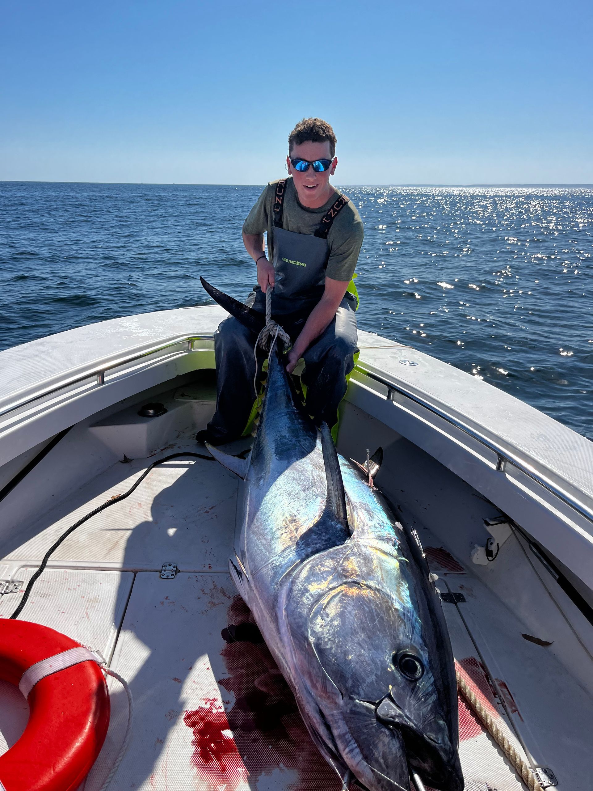 A man is sitting on a boat holding a large fish.