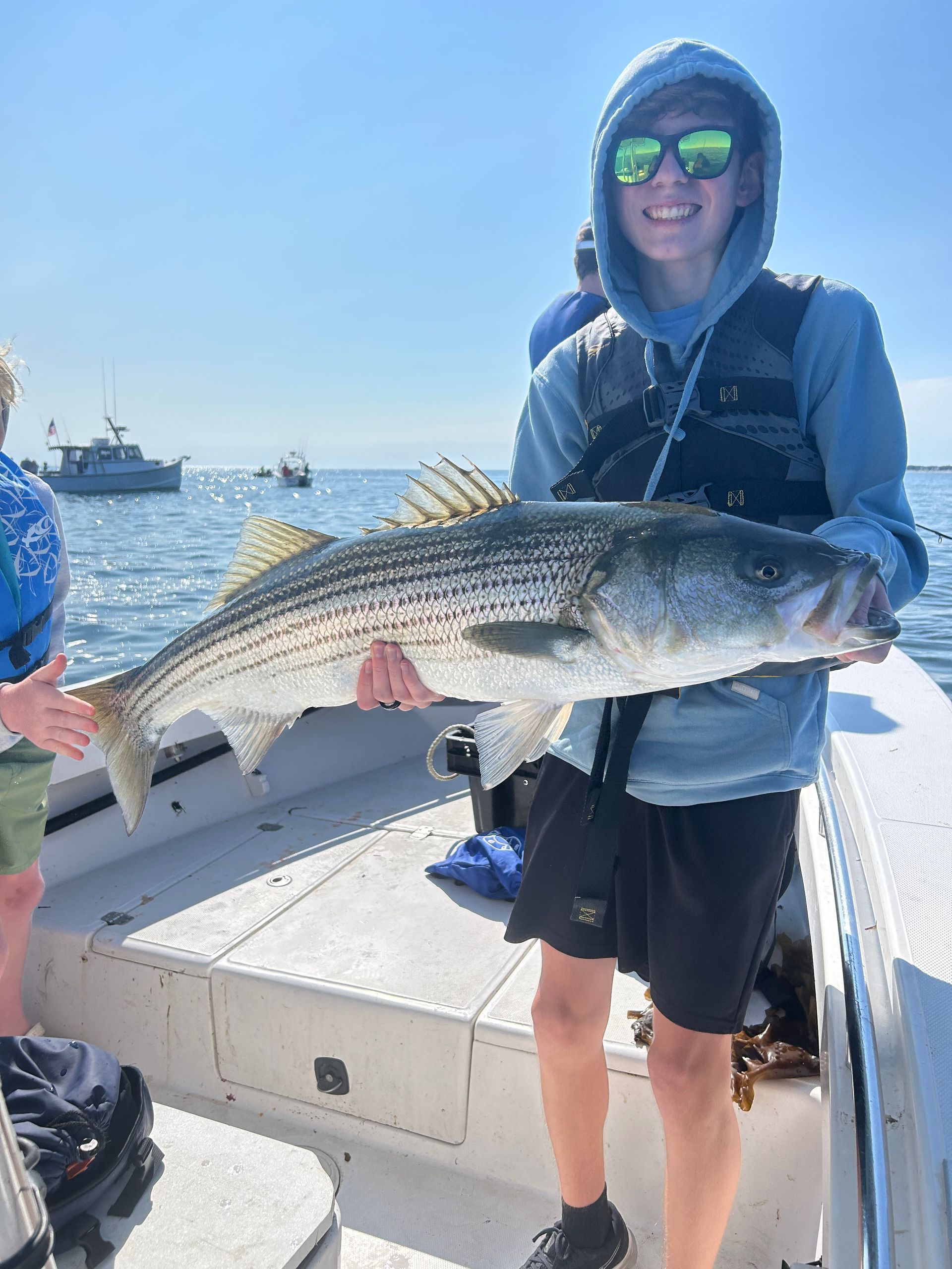 A man is holding a large fish on a boat.