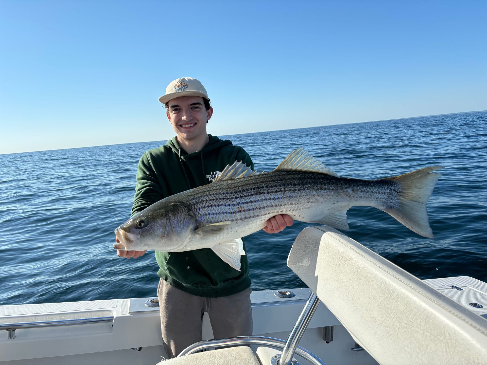 A man is holding a large fish on a boat in the ocean.