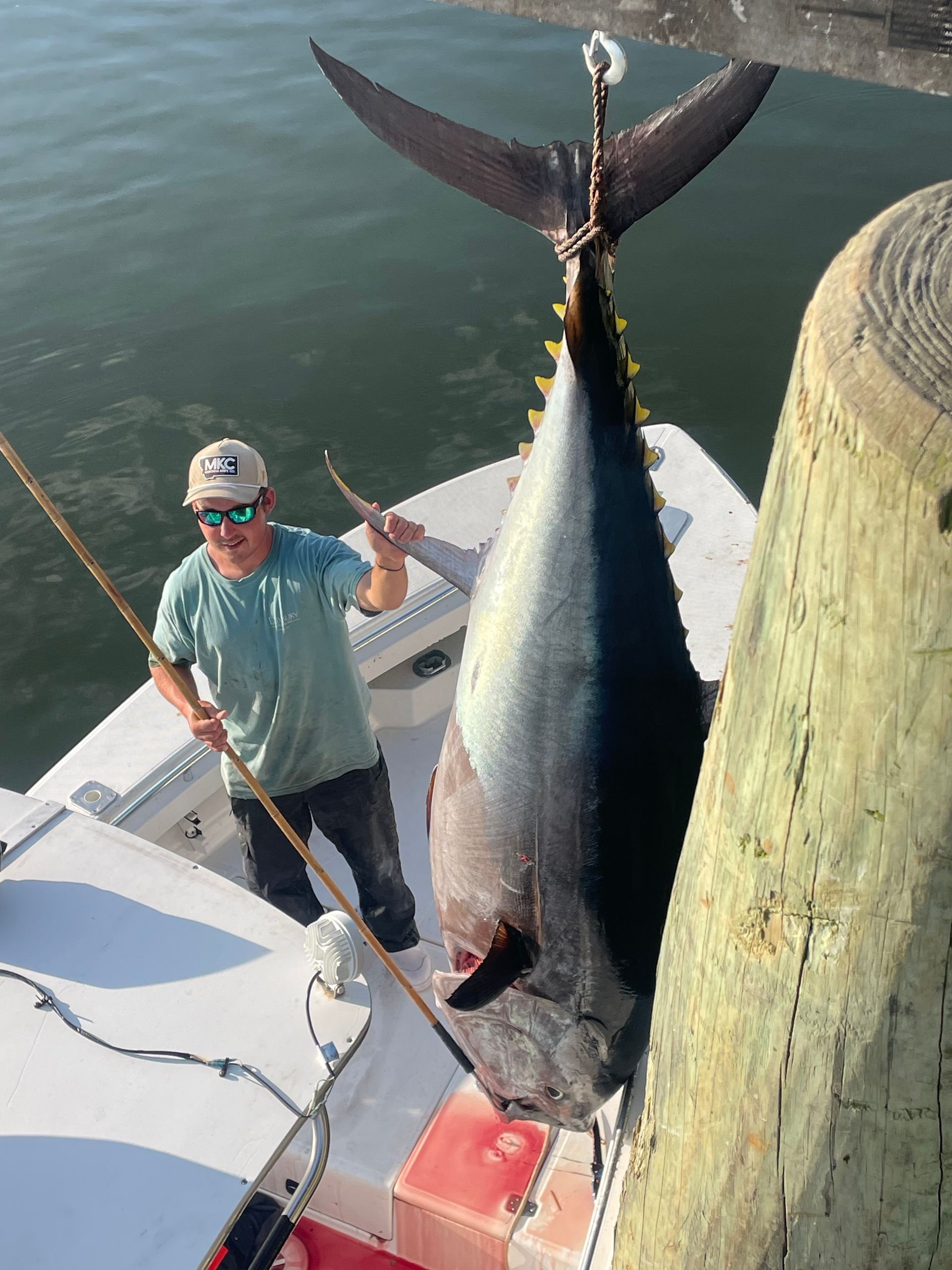 A man is standing on a boat holding a large fish.
