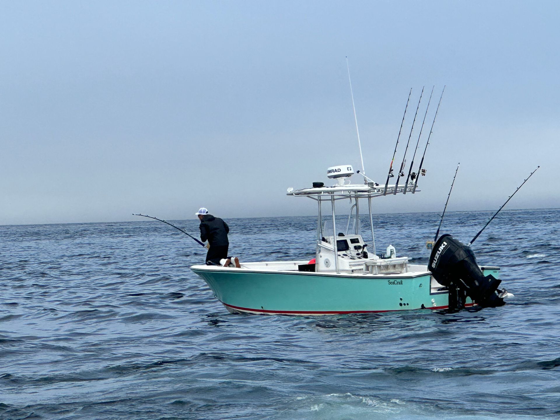 Two men are fishing on a boat in the ocean.