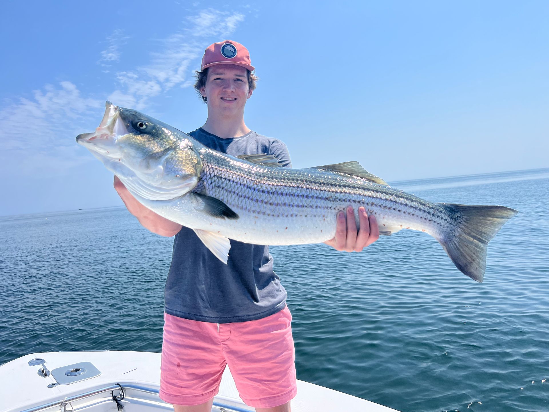 A young man is holding a large fish on a boat.
