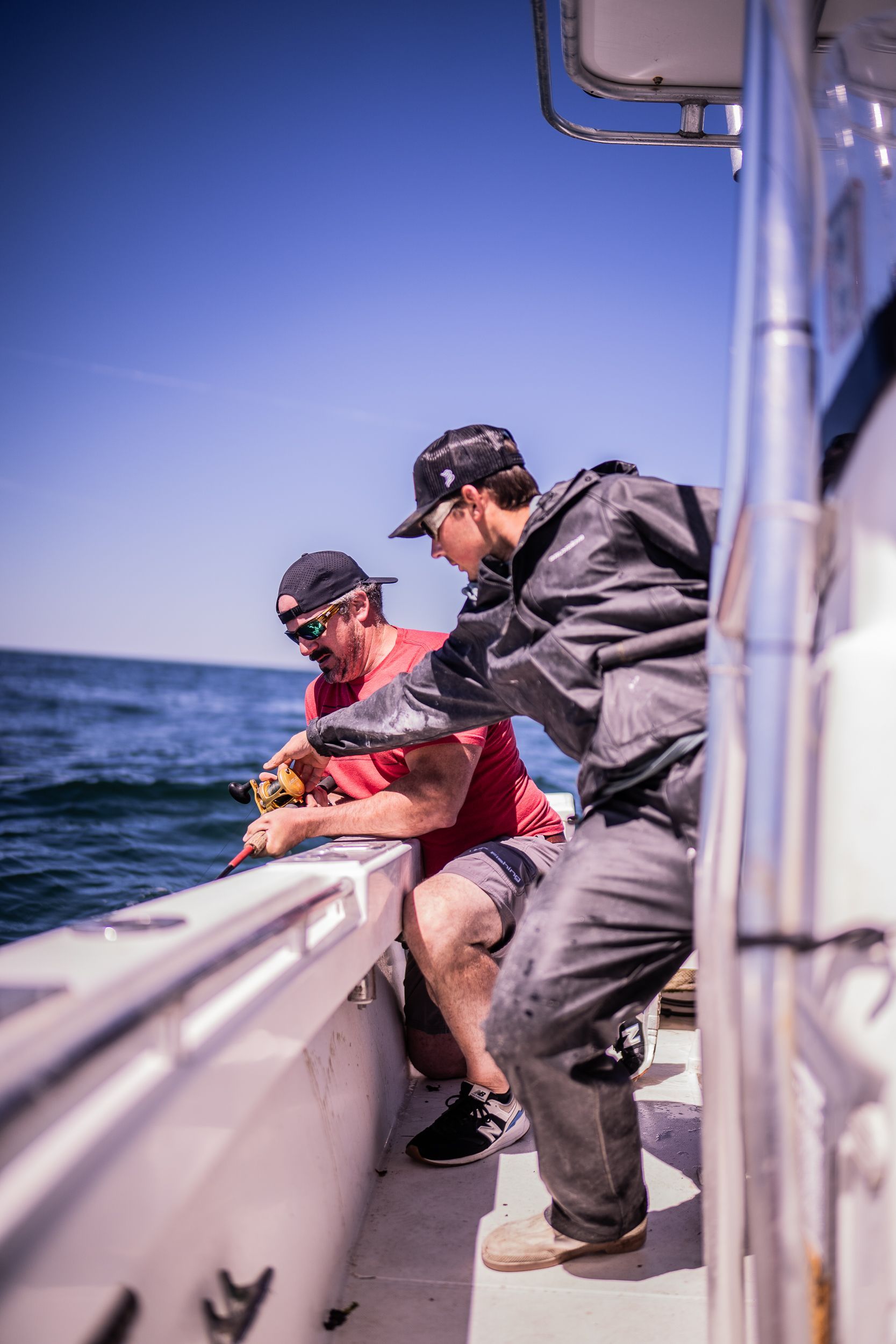 Two men are fishing on a boat in the ocean.