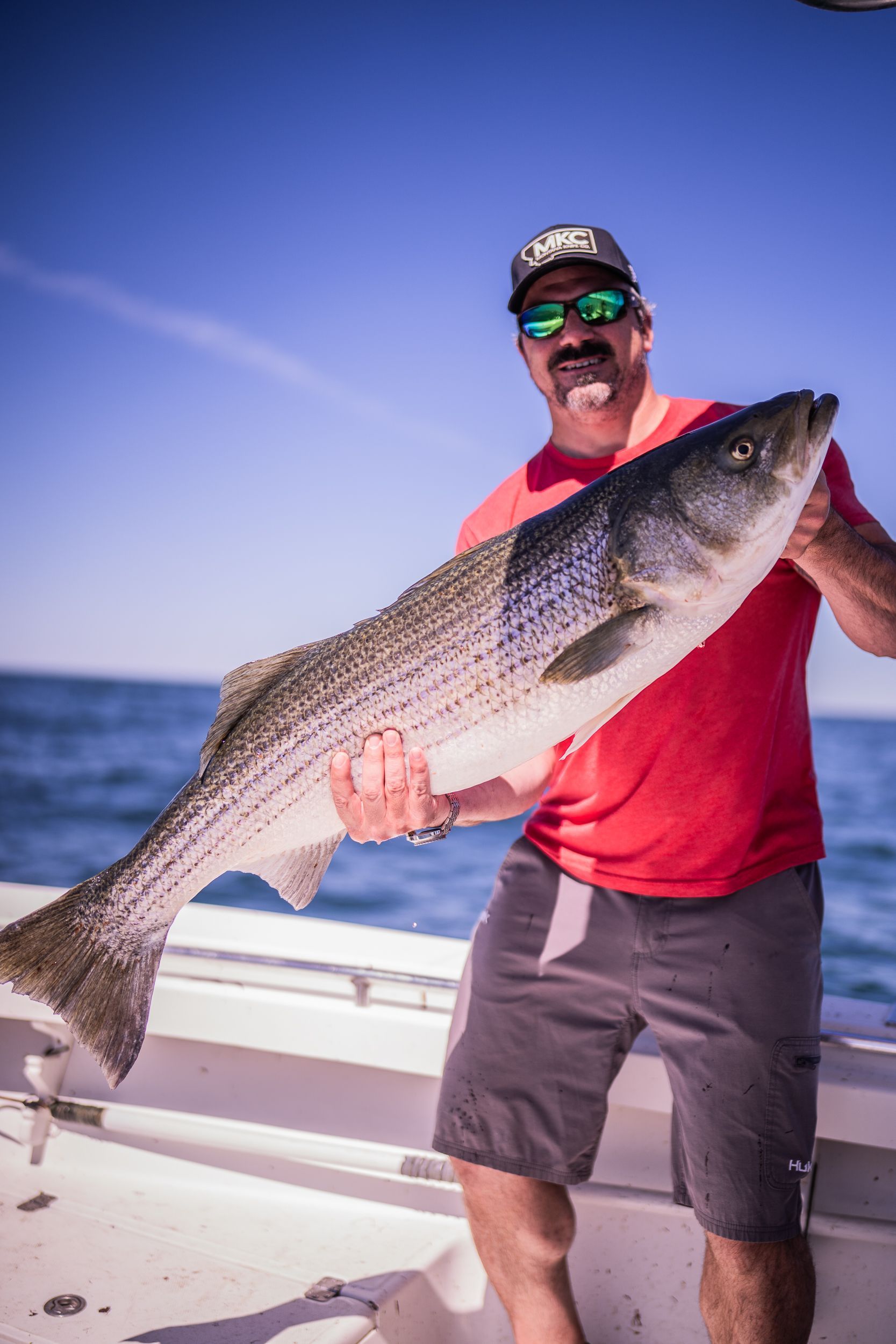 A man is holding a large fish on a boat.