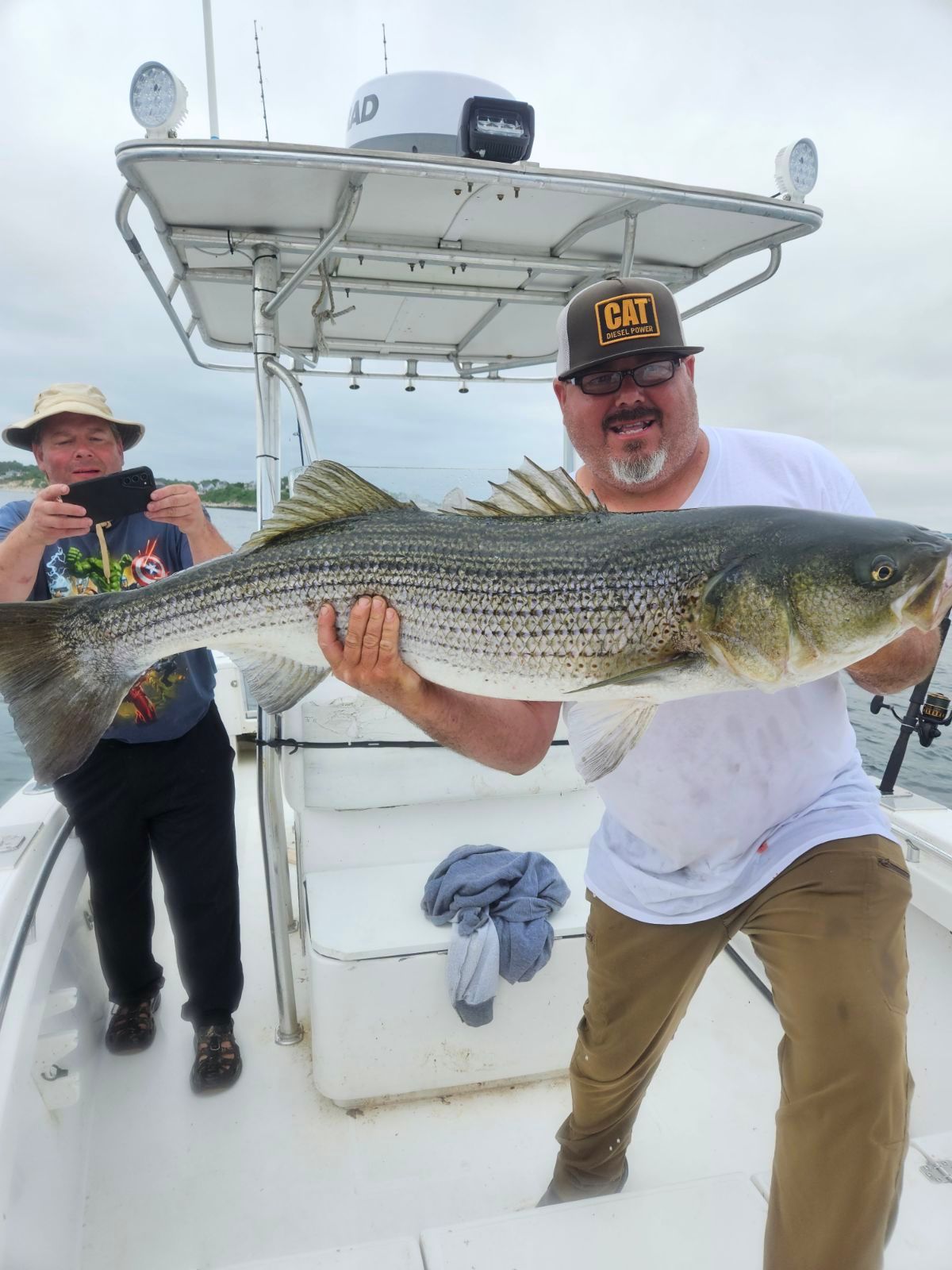 A man is holding a large fish on a boat.