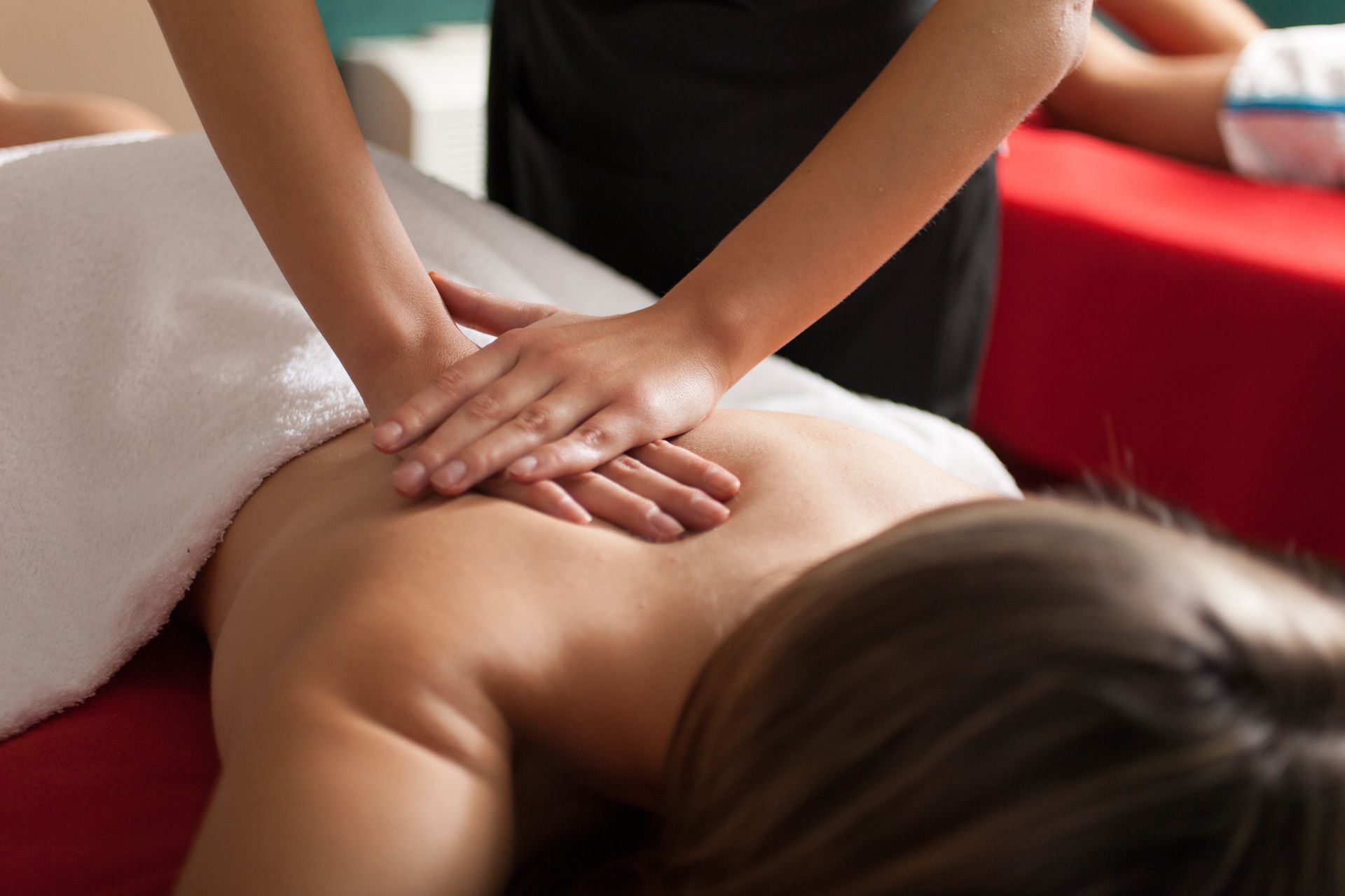 Massage therapist pressing on a client’s back during a spa treatment