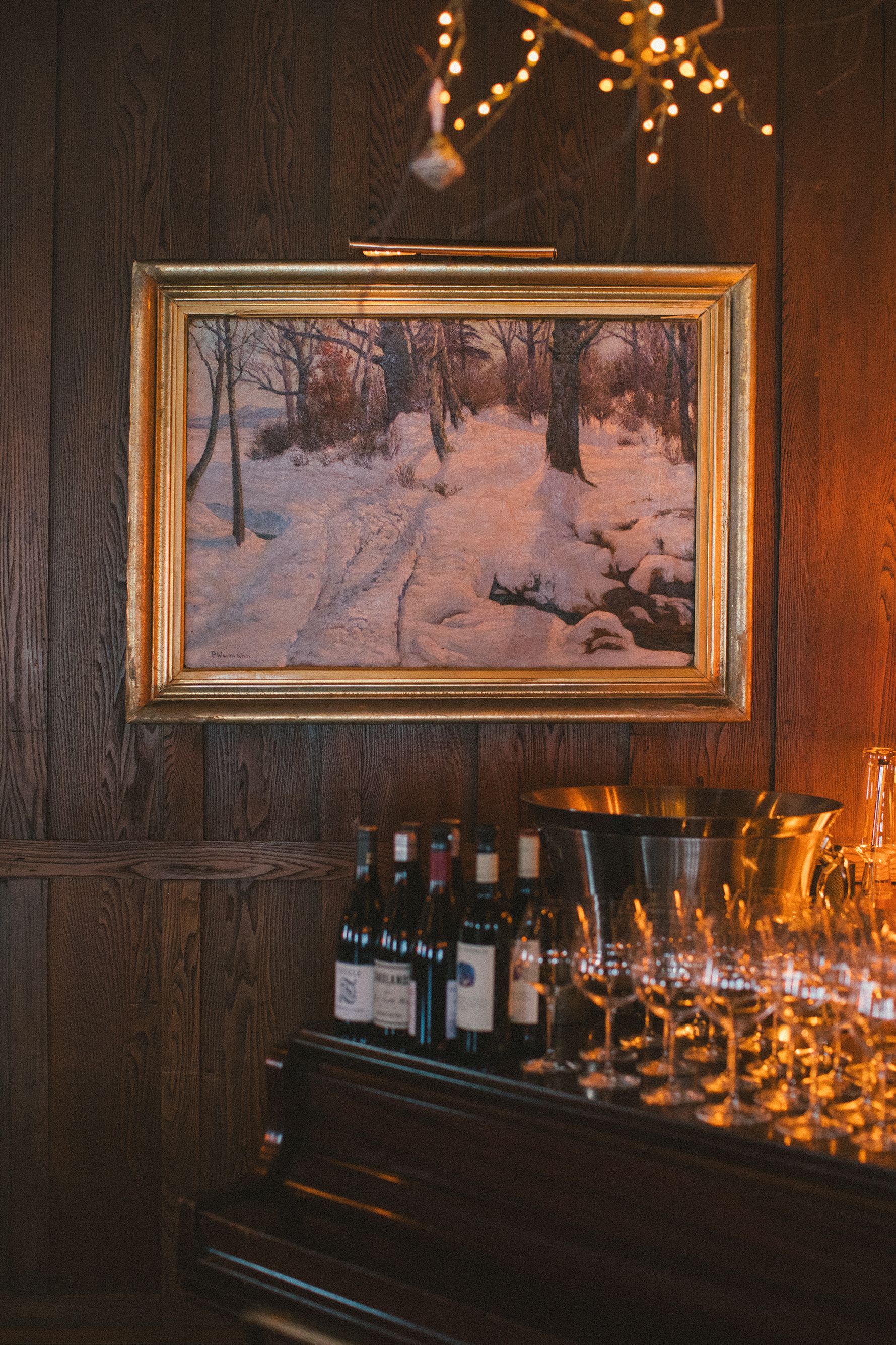 A painting of a snowy forest is hanging on a wall above a piano.