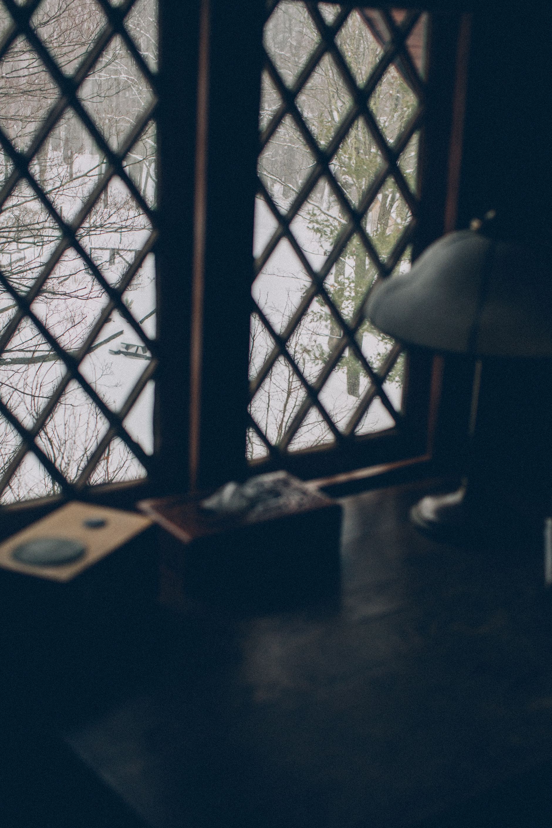 A lamp is sitting in front of a window in a dark room.